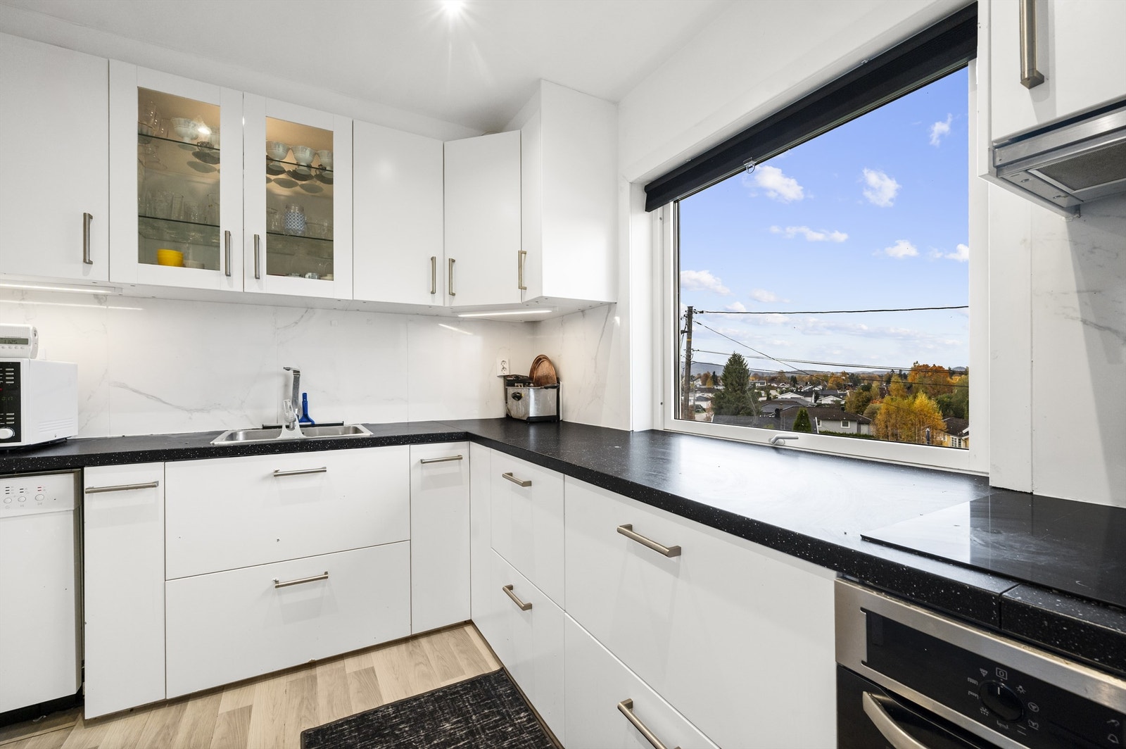 Kjøkkeninnredning er fra 2022 og er innredet med glatte fronter, fliser på vegg over benkeskap, ventilator med avtrekk gjennom yttervegg og laminat benkeplate. Galleribilde