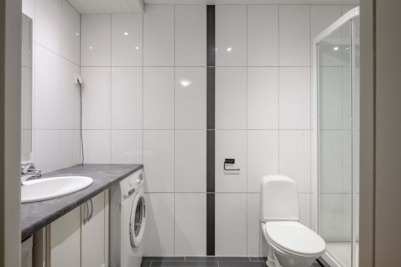 Baderommet er innredet med toalett og dusjkabinett. Mekanisk ventilasjon og downlights i himling. Galleribilde