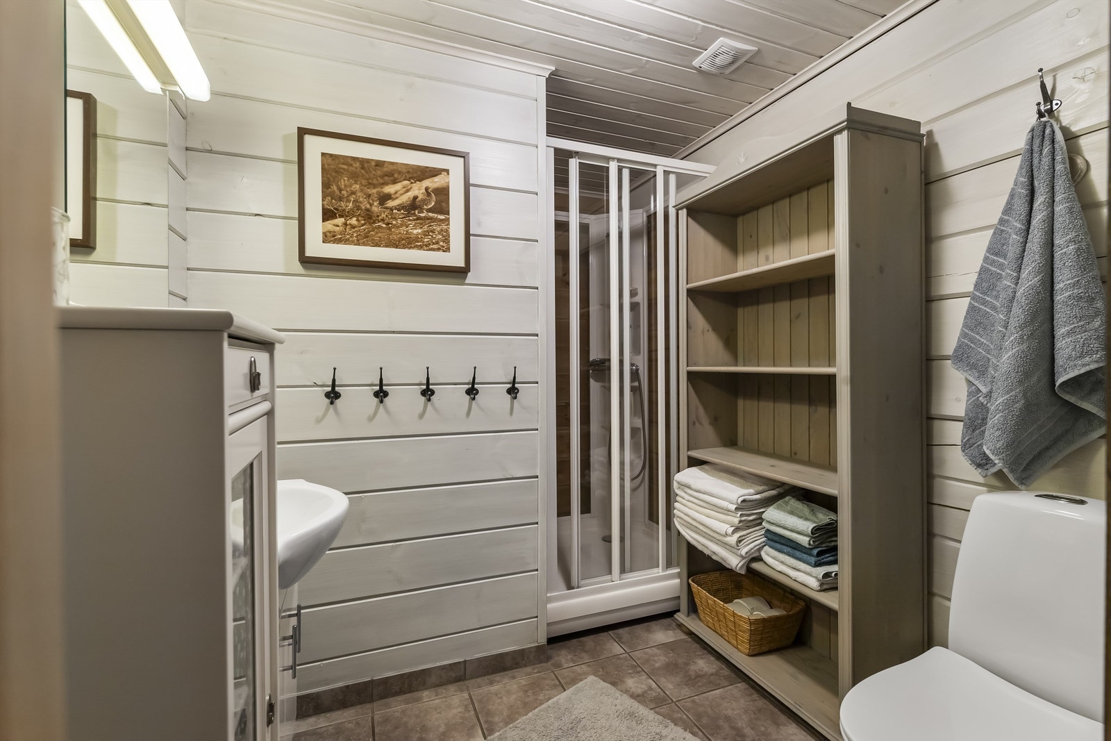 Bad er tidløst og praktisk innredet med dusjkabinett, servant i innredning og toalett Galleribilde