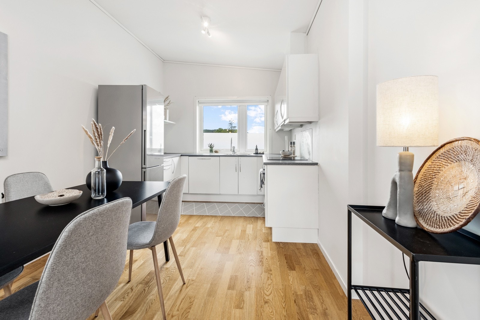 Hvit kjøkkeninnredning med slette fronter og integrerte hvitevarer som stekeovn, platetopp og oppvaksmaskin Galleribilde