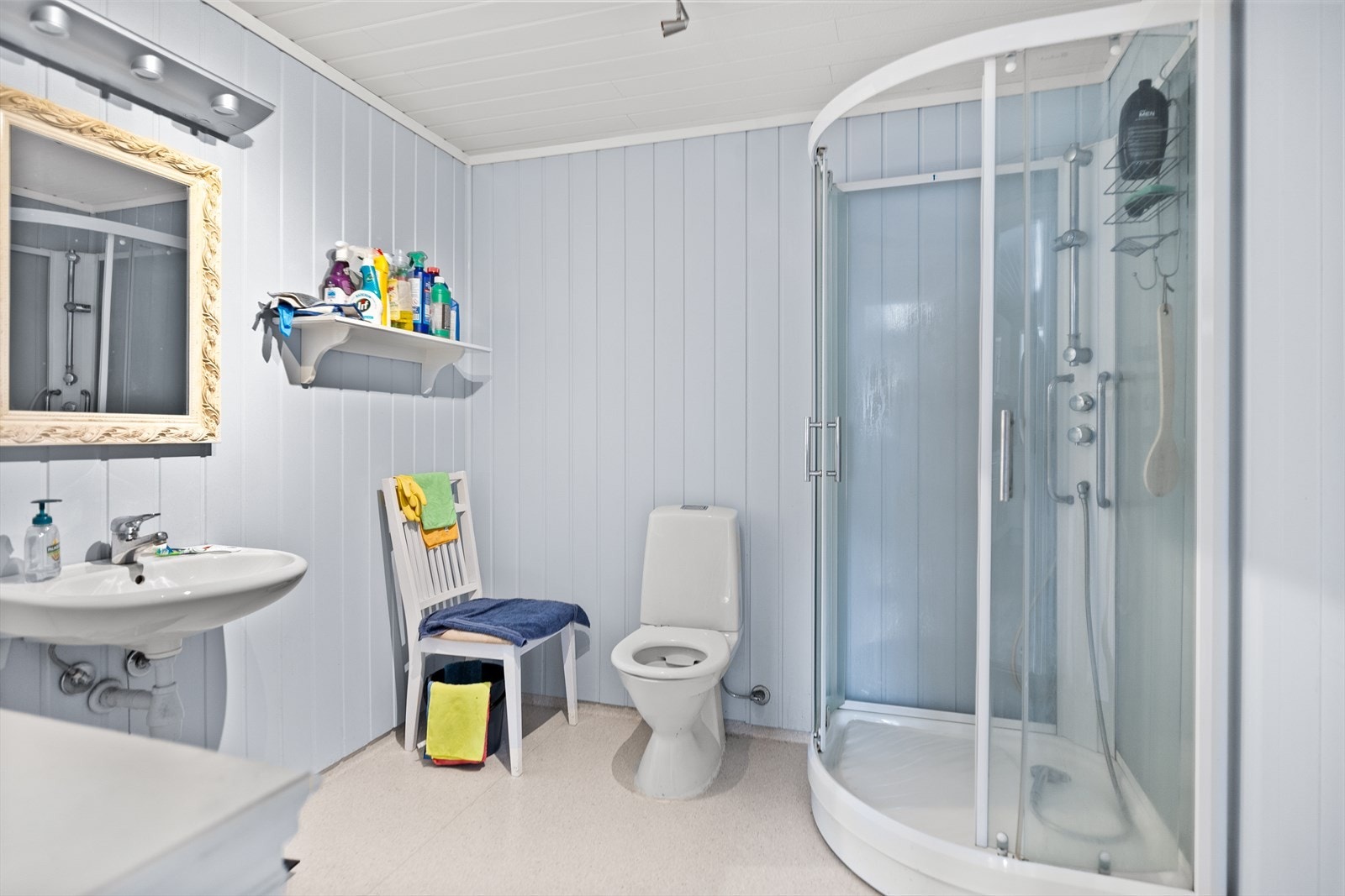 Badet i leiligheten med dusjkabinett, servant og gulvmontert toalett. Toalettet trenger nytt sete. Galleribilde