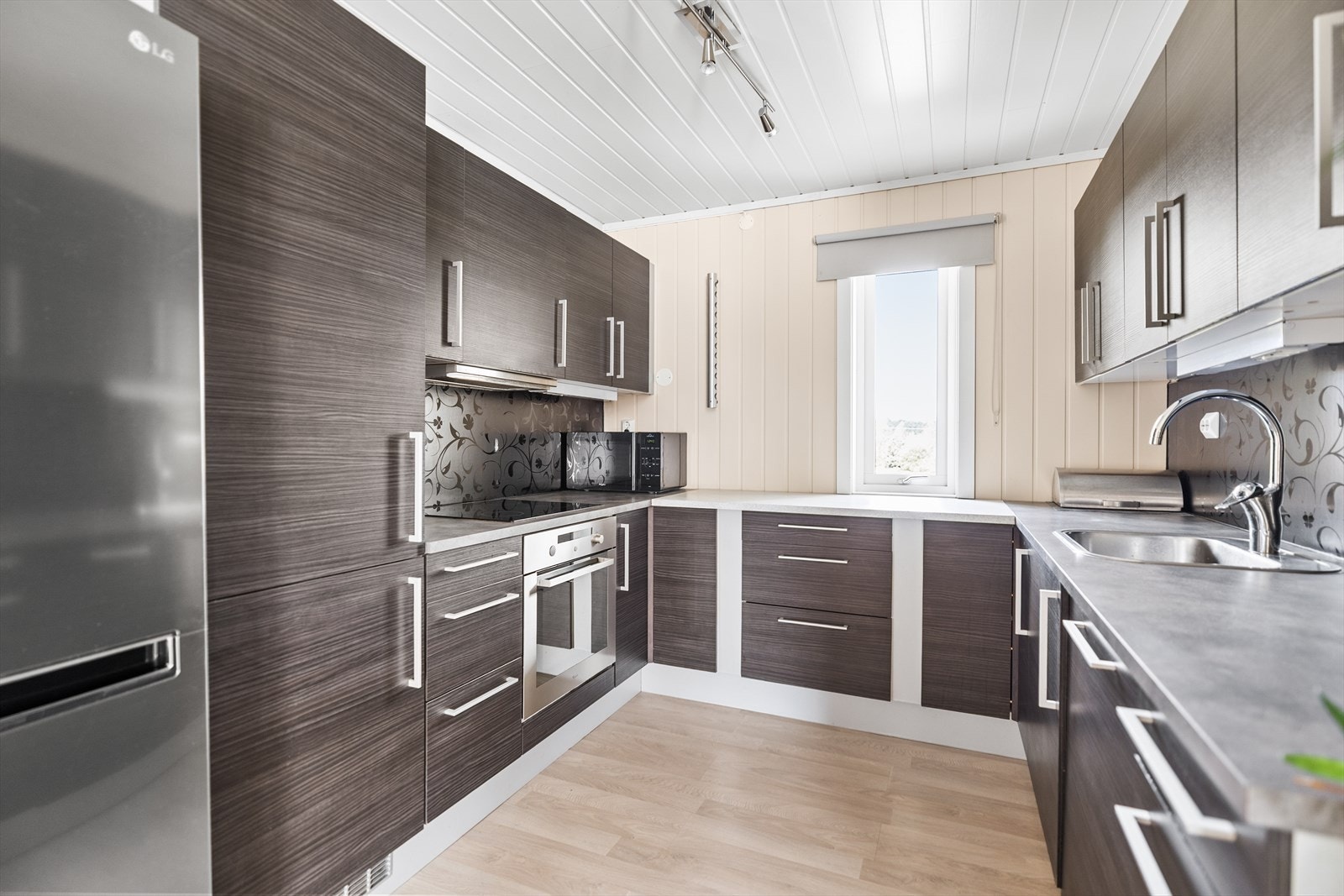 Kjøkkeninnredning med glatte fronter og benkeplate i høytrykkslaminat med nedfelt oppvaskkum i rustfritt stål. Galleribilde