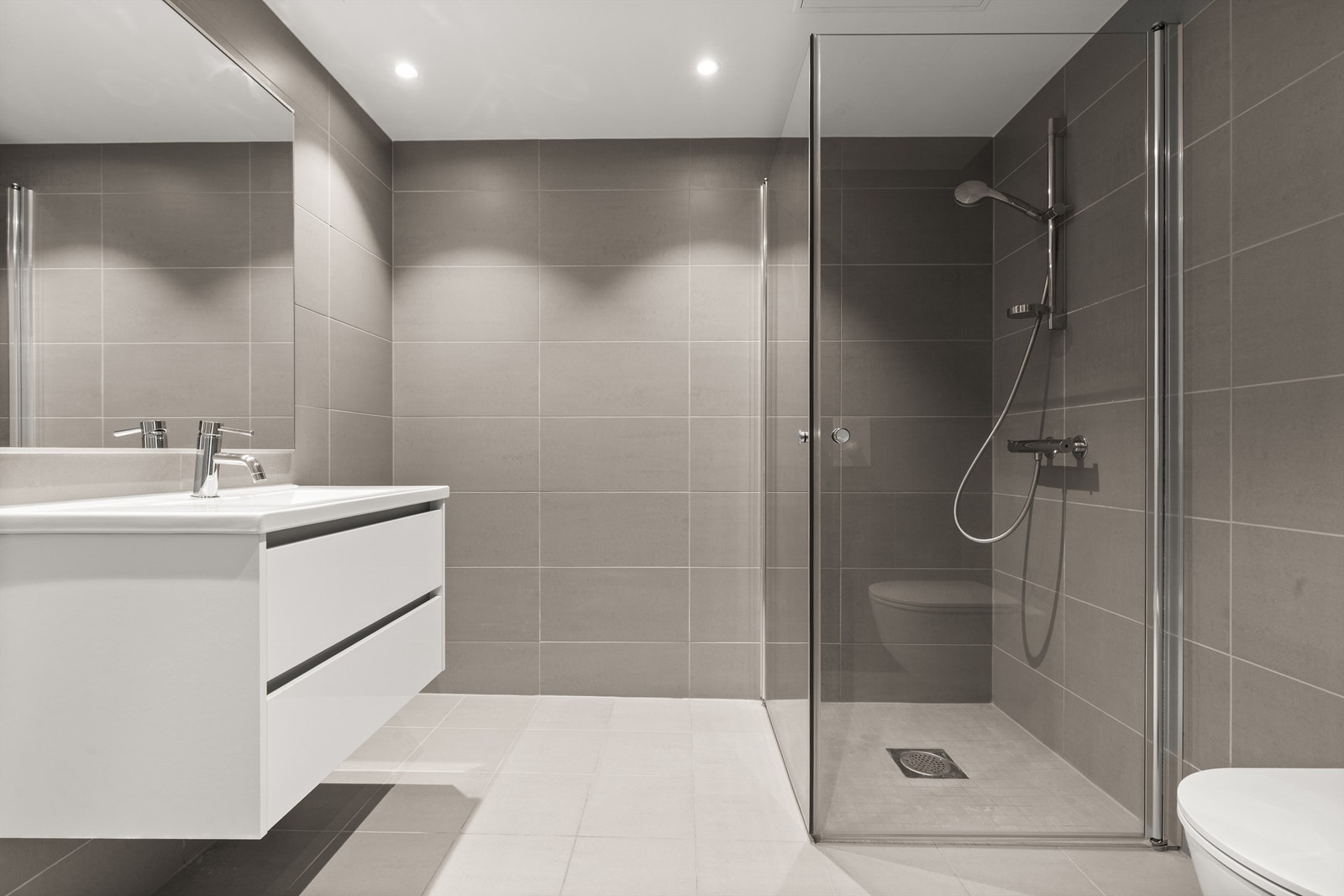 Videre har badet dusjhjørne med svingbare glassdører og vegghengt klosett. Det er opplegg for vaskemaskin. Galleribilde