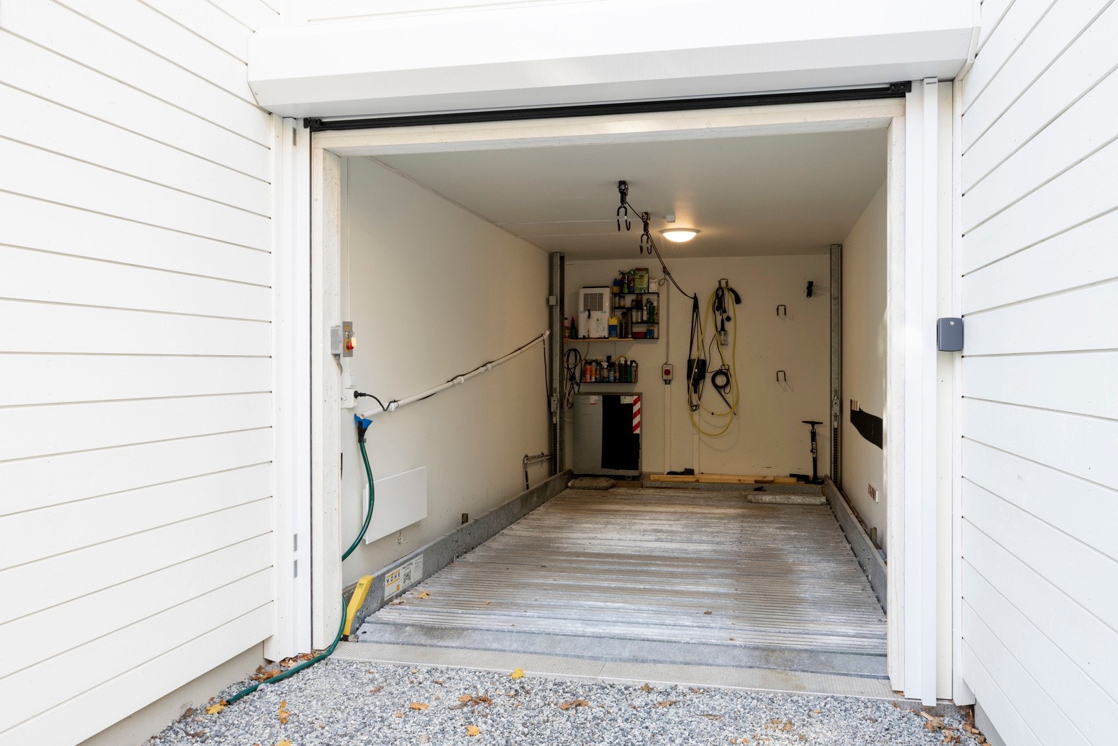 Boligen har to garasjerom med bilheis mellom, og en lader for elbil er installert i garasjeanlegget. Det følger også med en gruslagt p-plass mellom boligen og nabohuset. Galleribilde