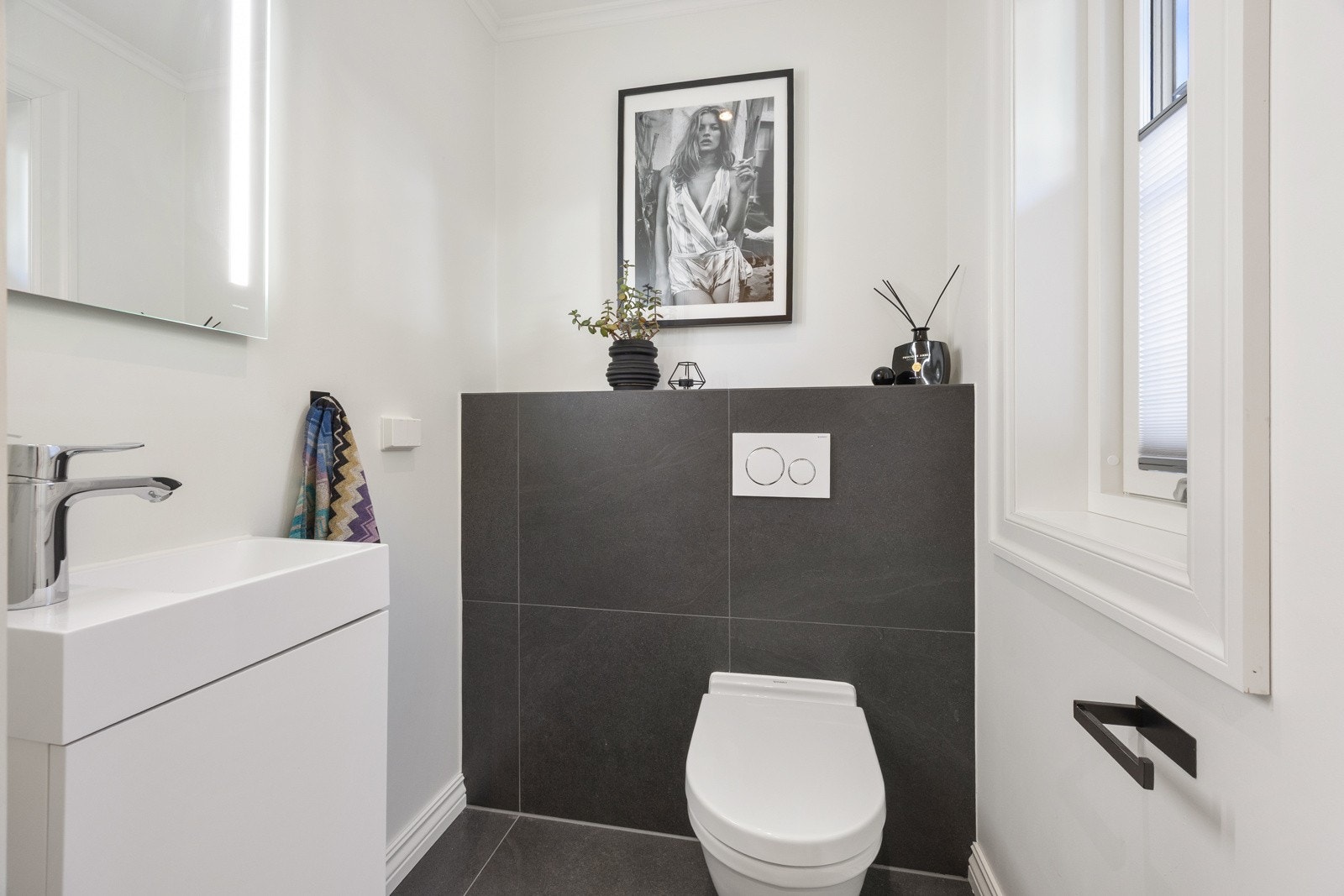 Gulvflisene fra hallen forsetter inn på et praktisk gjestetoalett med vegghengt wc. Galleribilde