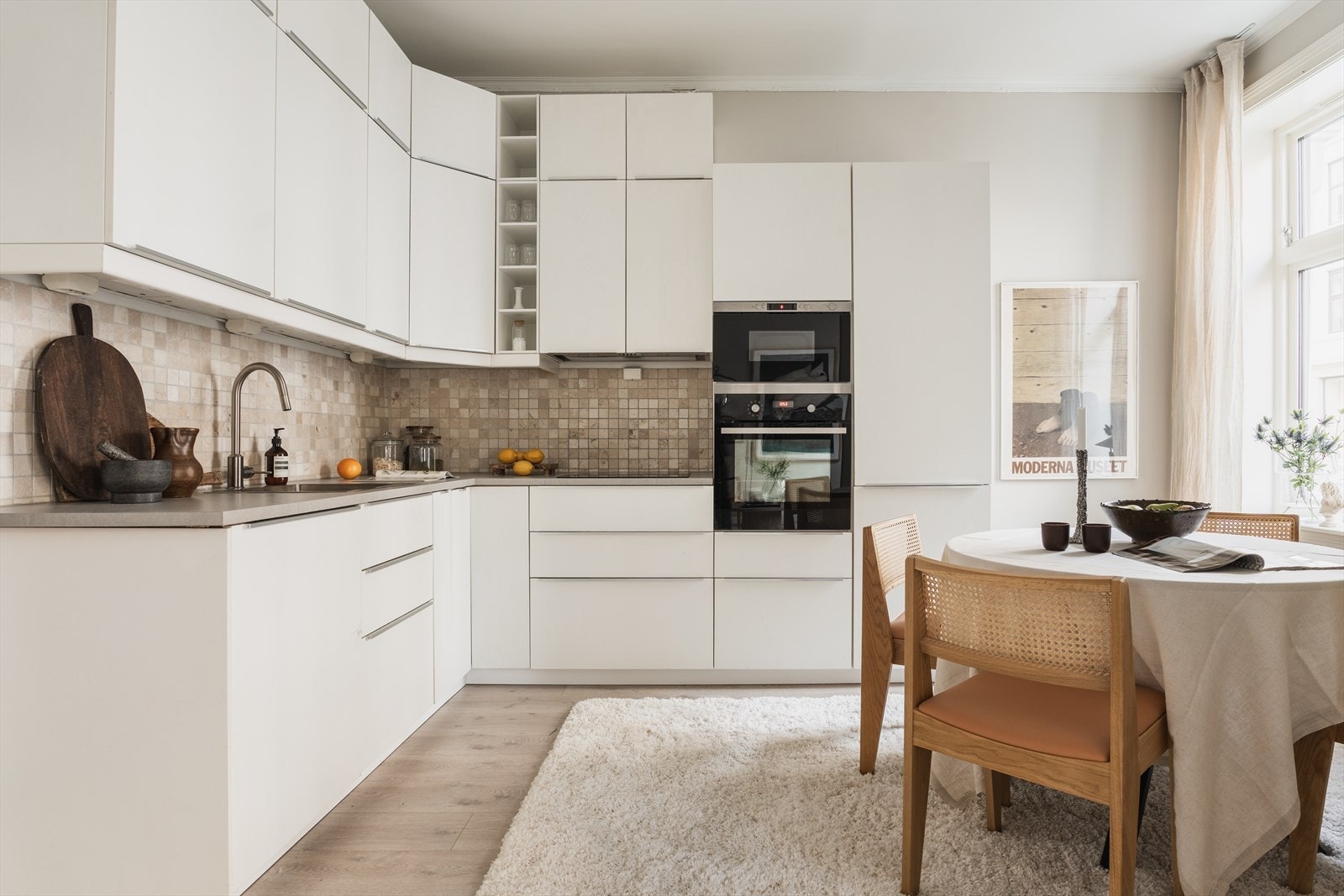 Lyst og lekkert kjøkken med slette fronter, fliser over kjøkkenbenk og integrerte hvitevarer Galleribilde