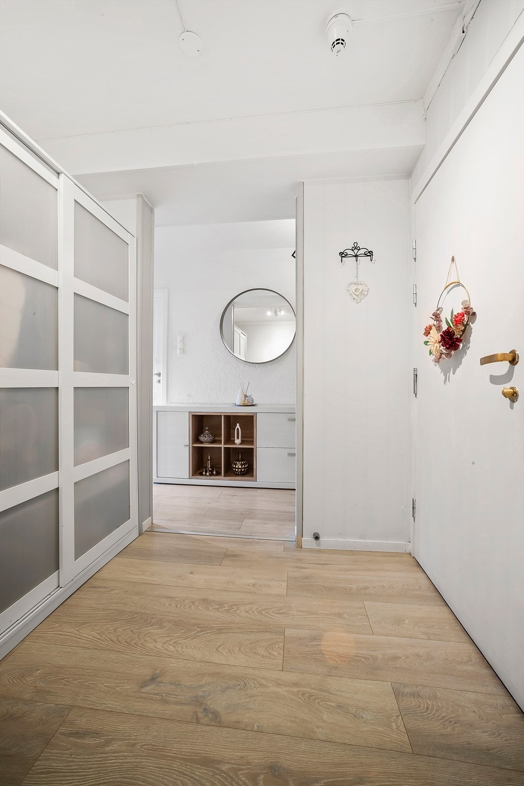 Man kommer inn i en lys og romslig entré med skyvedørsgarderobe Galleribilde