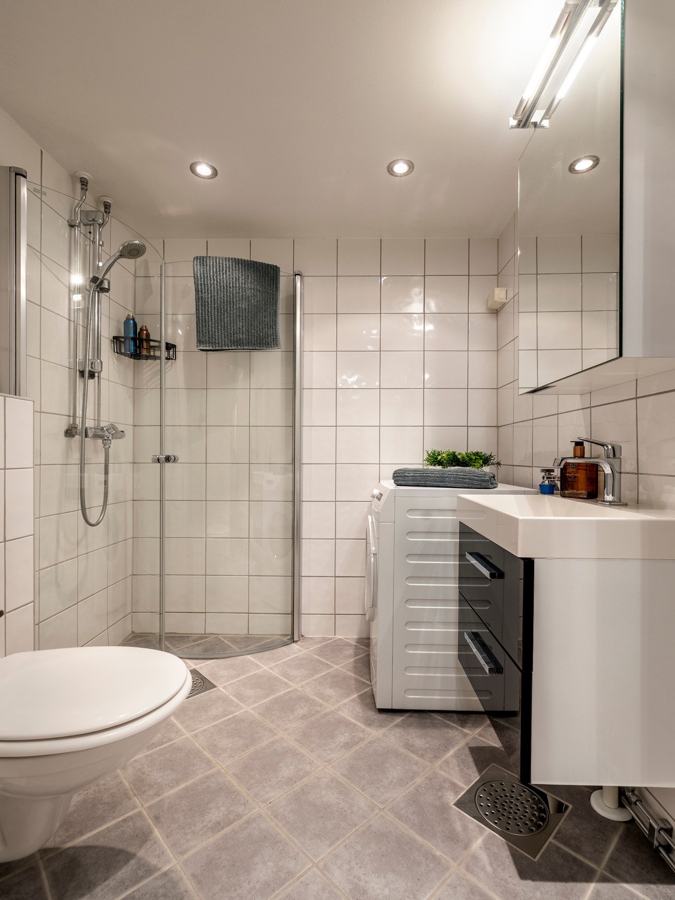 Innredningen består av servantinnredning, speil i dør på overskap på vegg over servant, vegghengt toalett og dusjhjørne med svingbare glassdører. Galleribilde