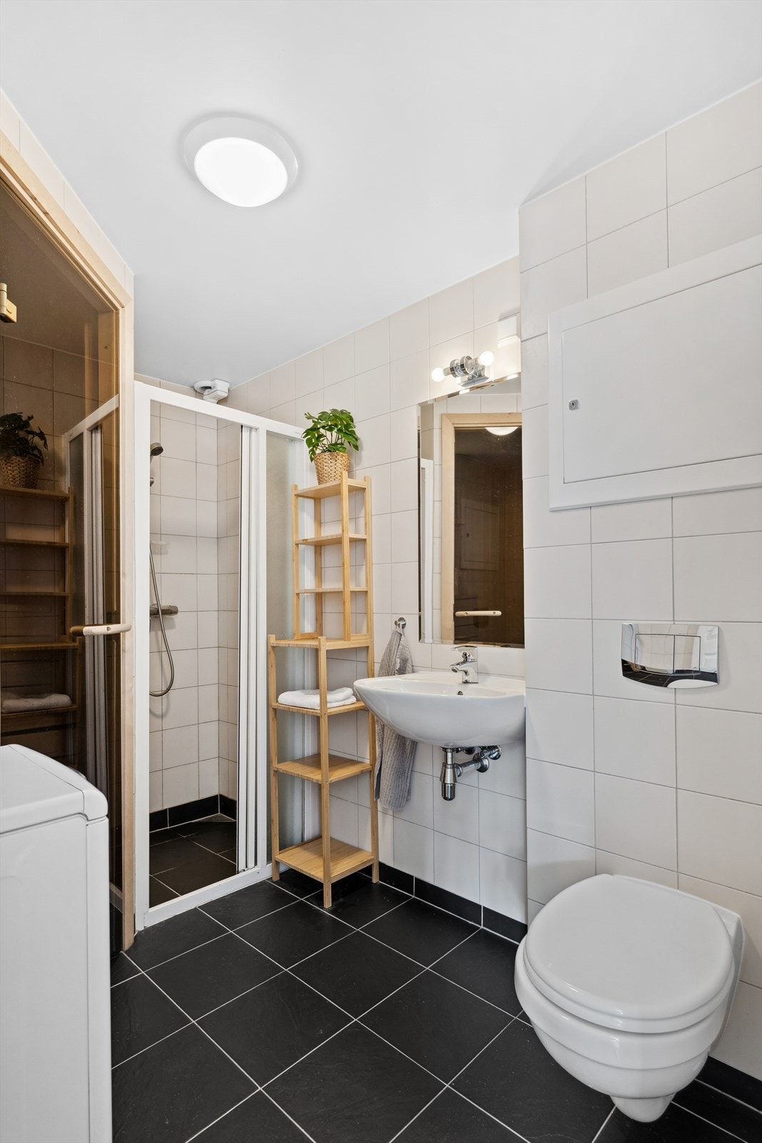 Flislagt bad med dusjvegger, toalett og baderomsinnredning med servant. Galleribilde