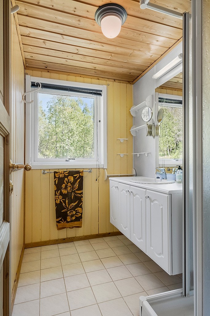 Badet har fliser i gulv og er utstyrt med servant m/ servantinnredning og dusjkabinett. Galleribilde