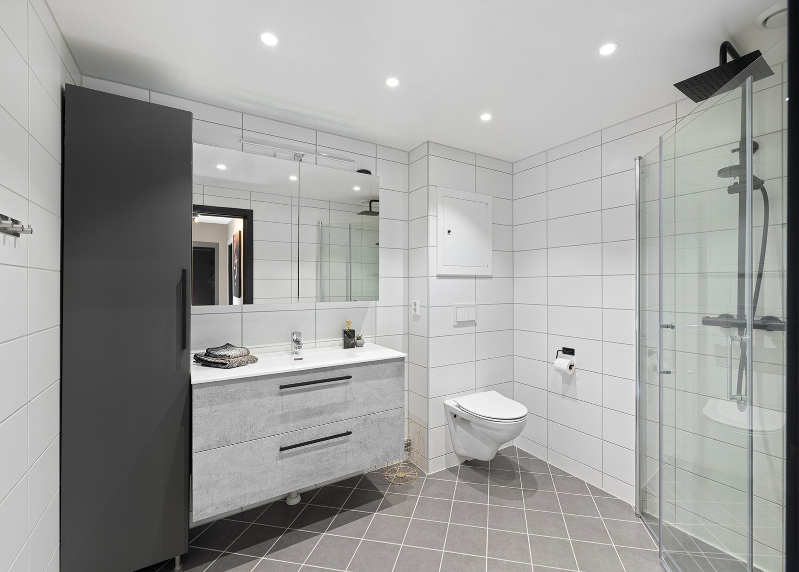 Stilrent og romslig bad fra 2022 med flislagte overflater og gulvvarme. Dusjhjørne med innfellbare glassdører, vegghengt toalett, moderne servantinnredning med god lagringsplass samt speilskap med belysning. Galleribilde