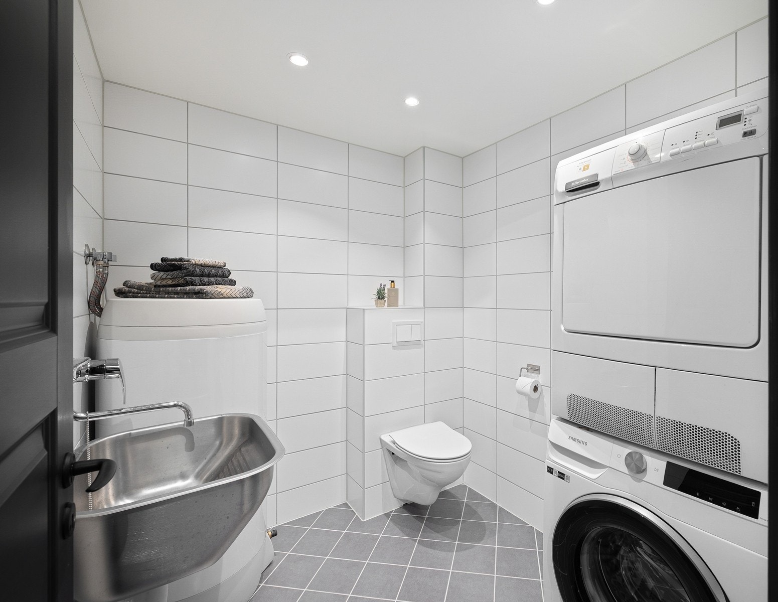 Praktisk vaskerom med opplegg for vaskemaskin og tørketrommel, samt utslagsvask og varmtvannsbereder. Her er det gode arbeidsforhold og oppbevaringsmuligheter. Galleribilde