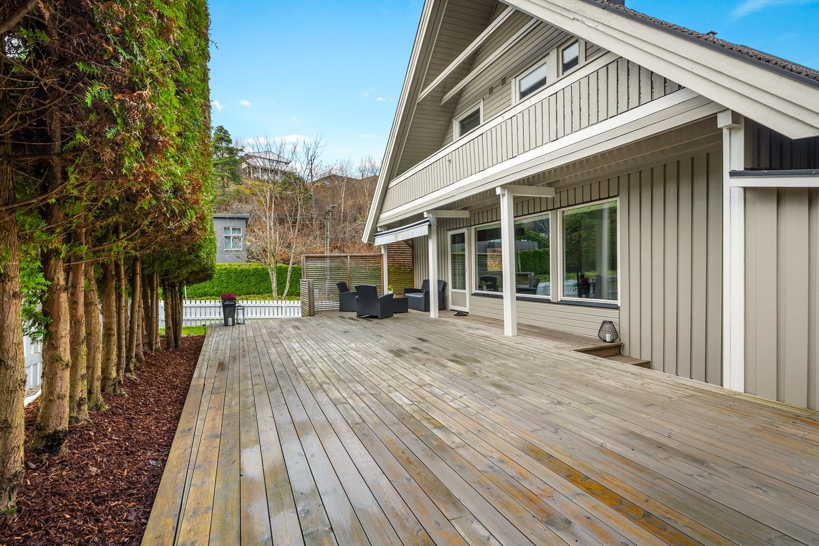 Tilgang fra stue til stor sørvendt terrasse med rekkverk med liggende spiler. på ca. 57 m2 gir romslig uteplass. Galleribilde