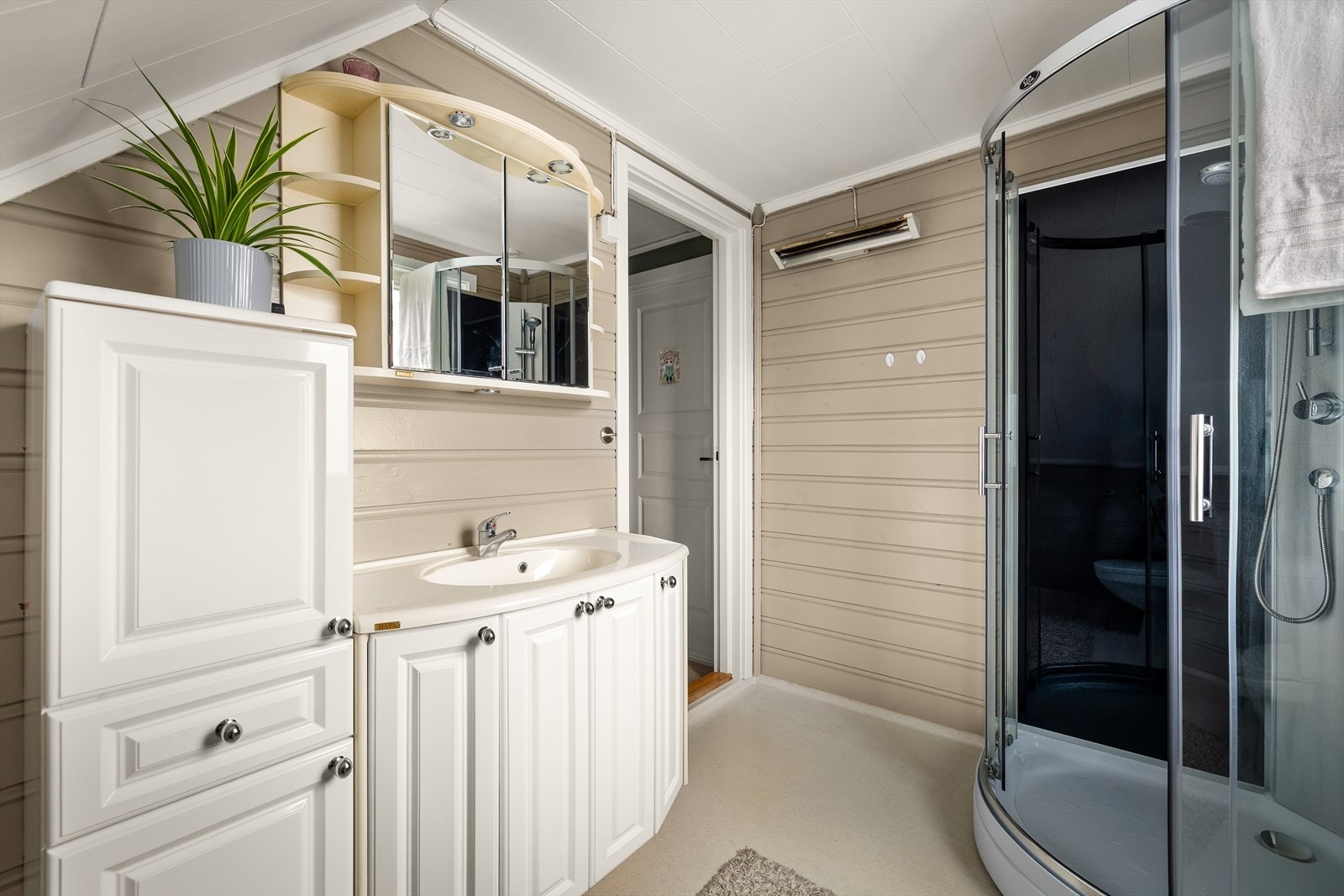 Badet har panel på vegger og belegg på gulv, med dusjkabinett og servantinnredning. Galleribilde