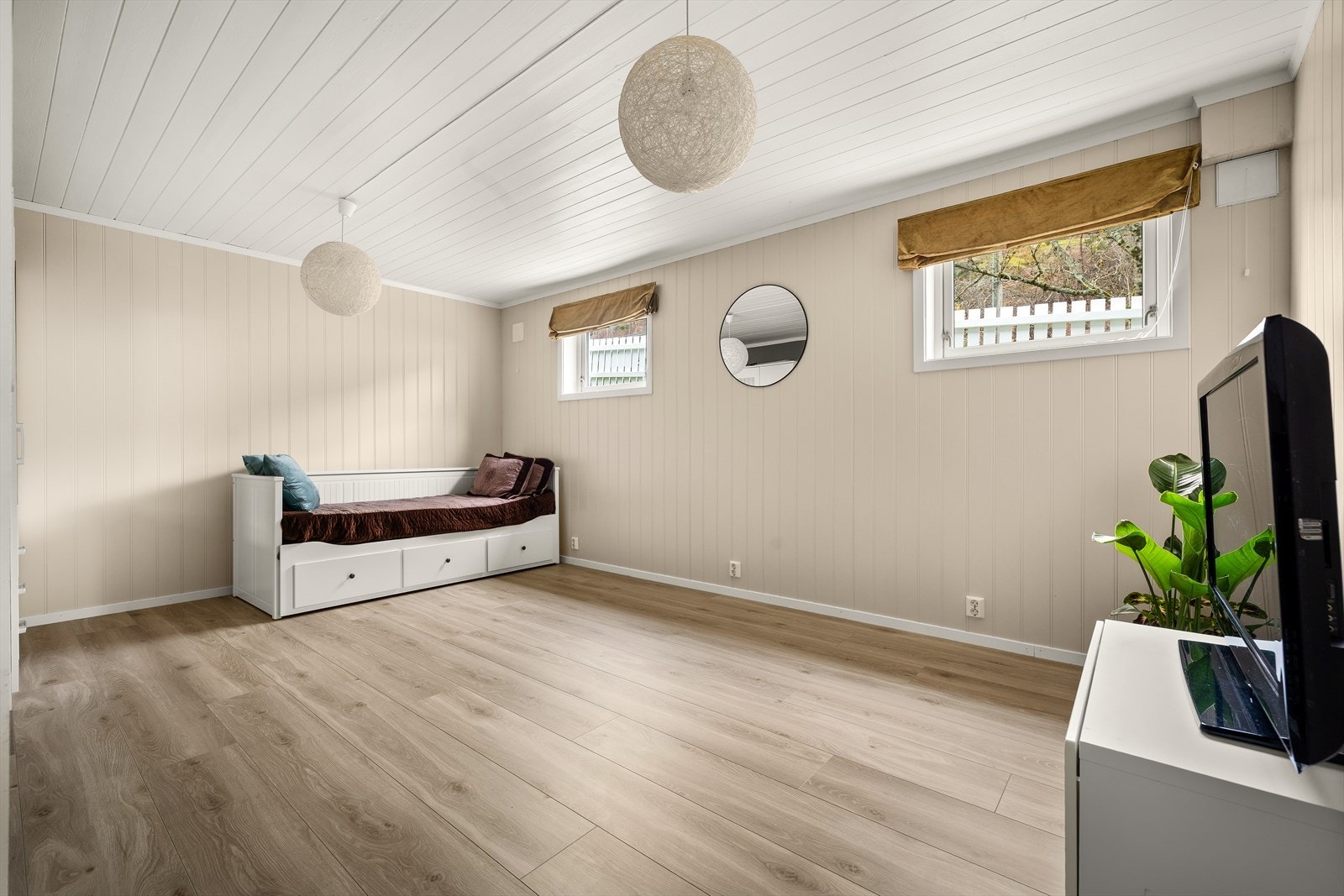 Vinduer med utsikt mot hageområde gir naturlig lys til rommet. Galleribilde