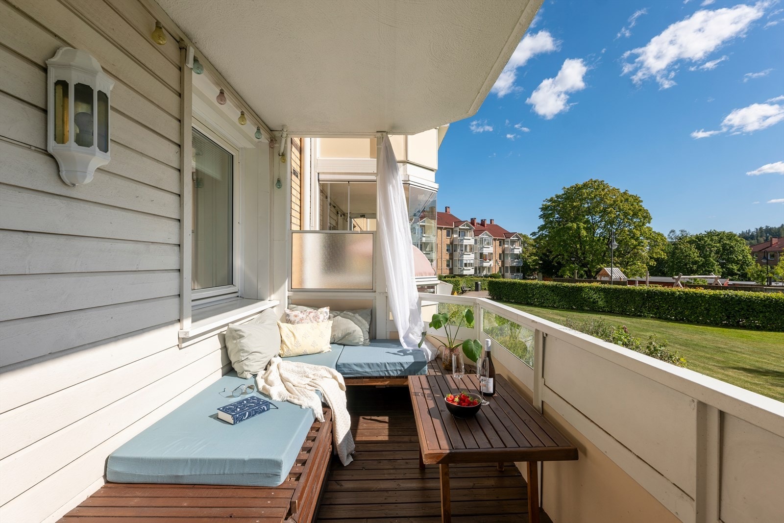 På balkongen er det beiset terassebord i trevirke og belysninge på vegg. Galleribilde