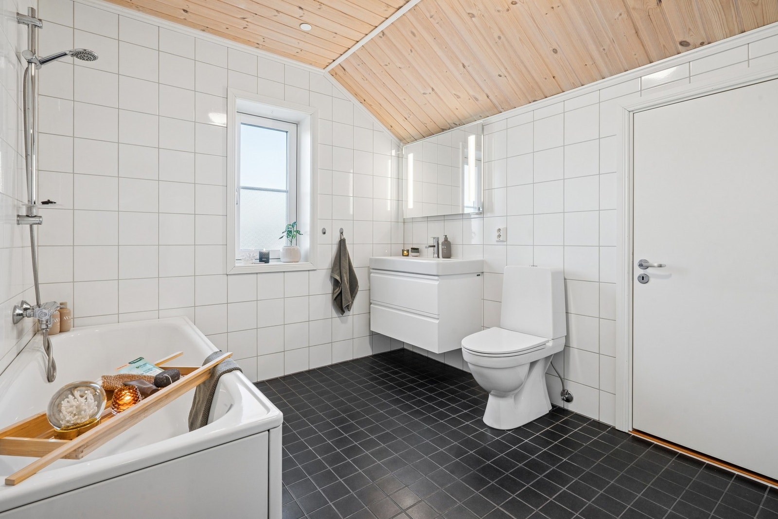 Flislagt gulv med varme og flislagte vegger. Innredning med servant med ett-greps armatur. Speil med belysning samt dobbel stikkontakt på vegg. Frittstående toalett. Frittstående badekar med ett-greps armatur med hånddusj. Galleribilde