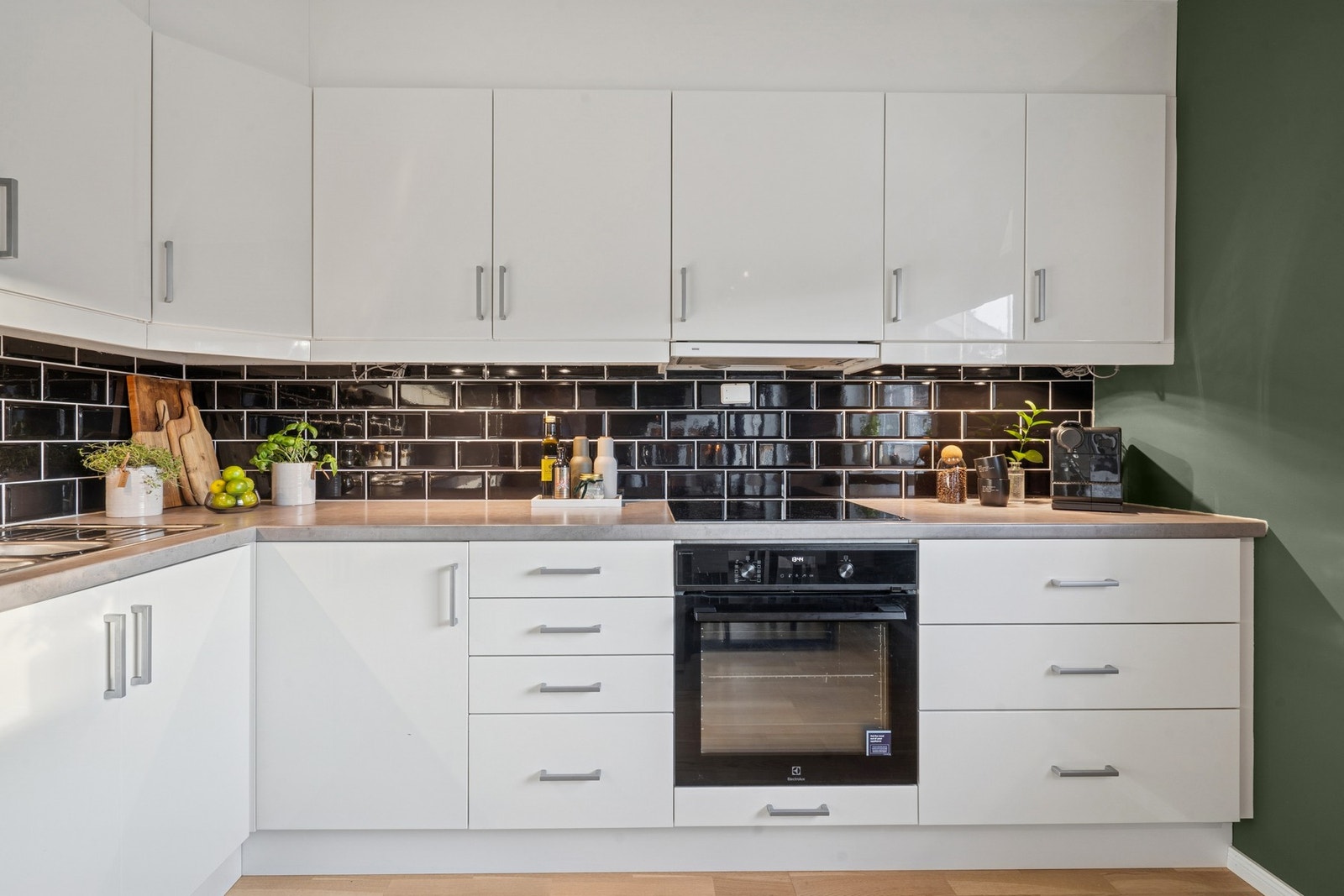 Kjøkkeninnredning med høyglans fronter og delvis integrerte hvitevarer. Overskap med belysning under og ventilator tilkoblet avtrekkskanal. Laminert benkeplate med skyllekum og oppvaskkum med ett-greps armatur samt induksjons koketopp. Galleribilde