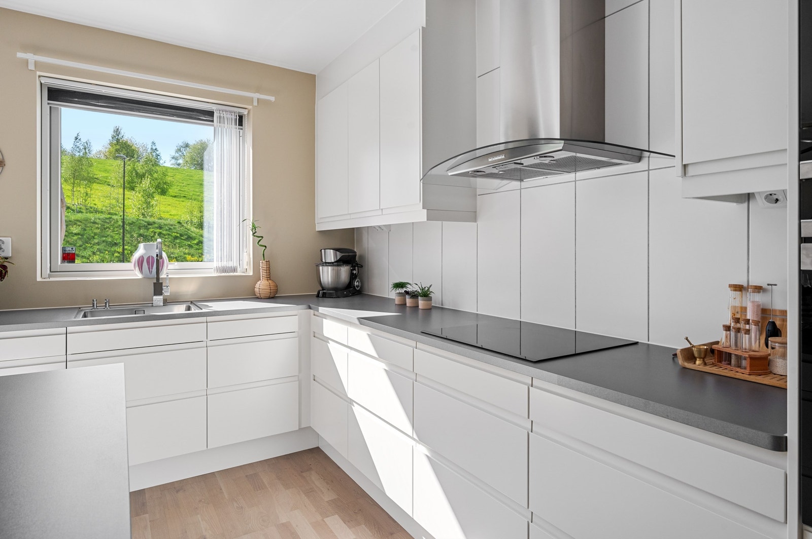 Innredningen består av hvite glatte fronter og laminat benkeplate med nedfelt vaskekum. Over kokeplassen er det lagt fliser som sørger for enkel rengjøring, samt belysning og avtrekk over kokeplassen. Galleribilde