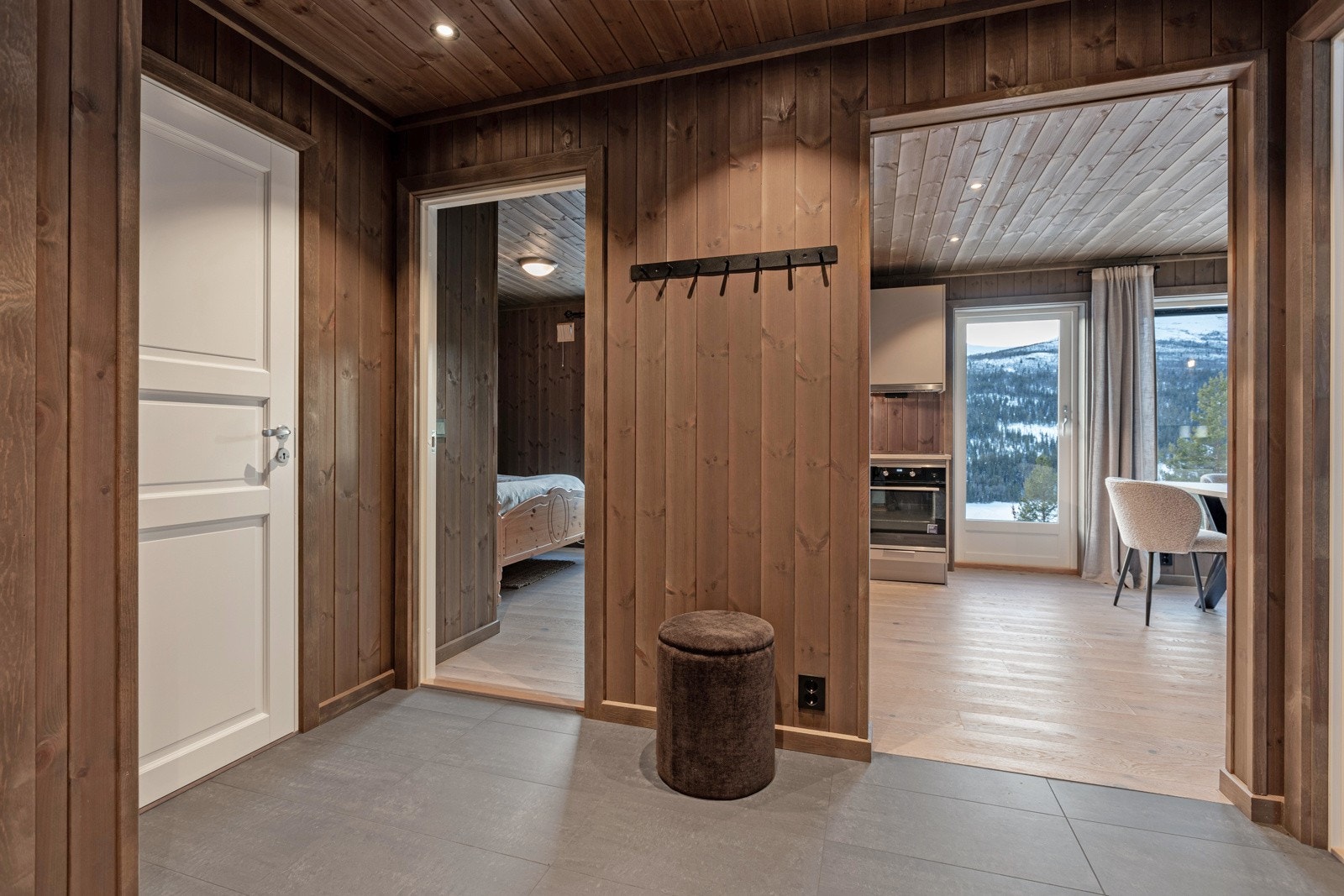 Her blir du ønsket velkommen inn i en innbydende og romslig entré, med fliser på gulv og trepanel på veggene. Galleribilde