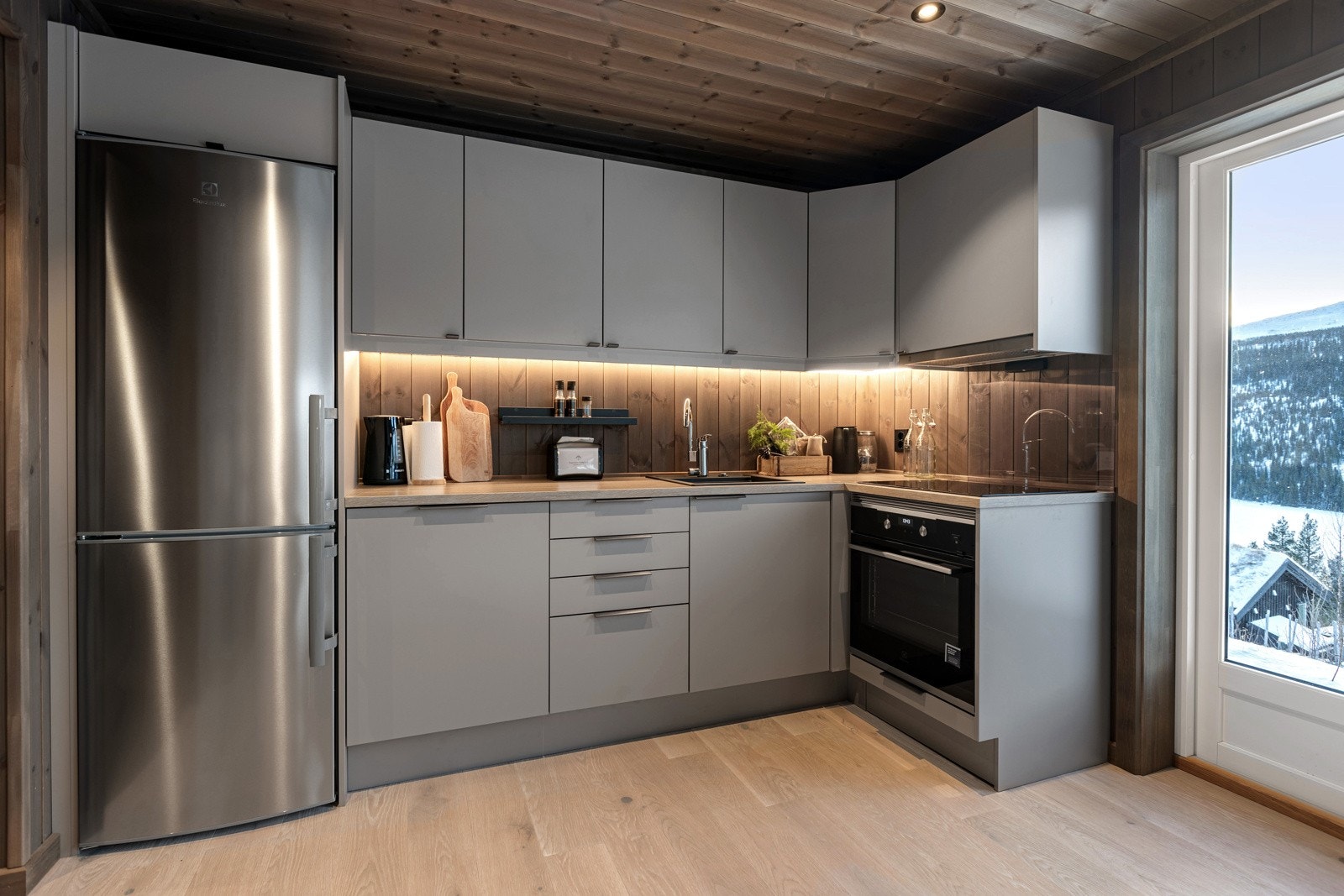 Kjøkkenet er innredet med glatte fronter i en delikat, beigefarge, og en solid benkeplate av laminat. Galleribilde