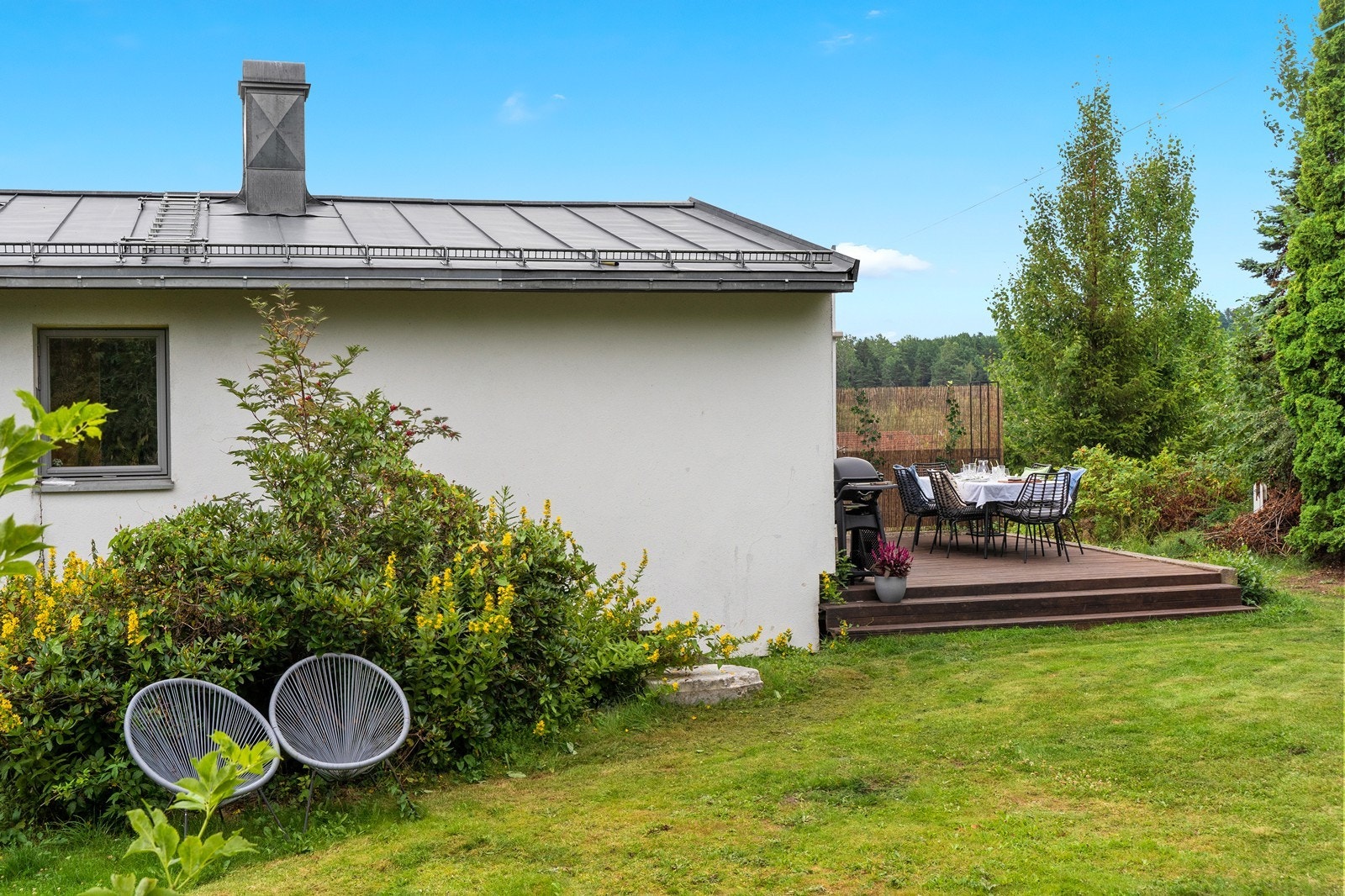 Grønn og frodig hage med flere sitteplasser. Galleribilde