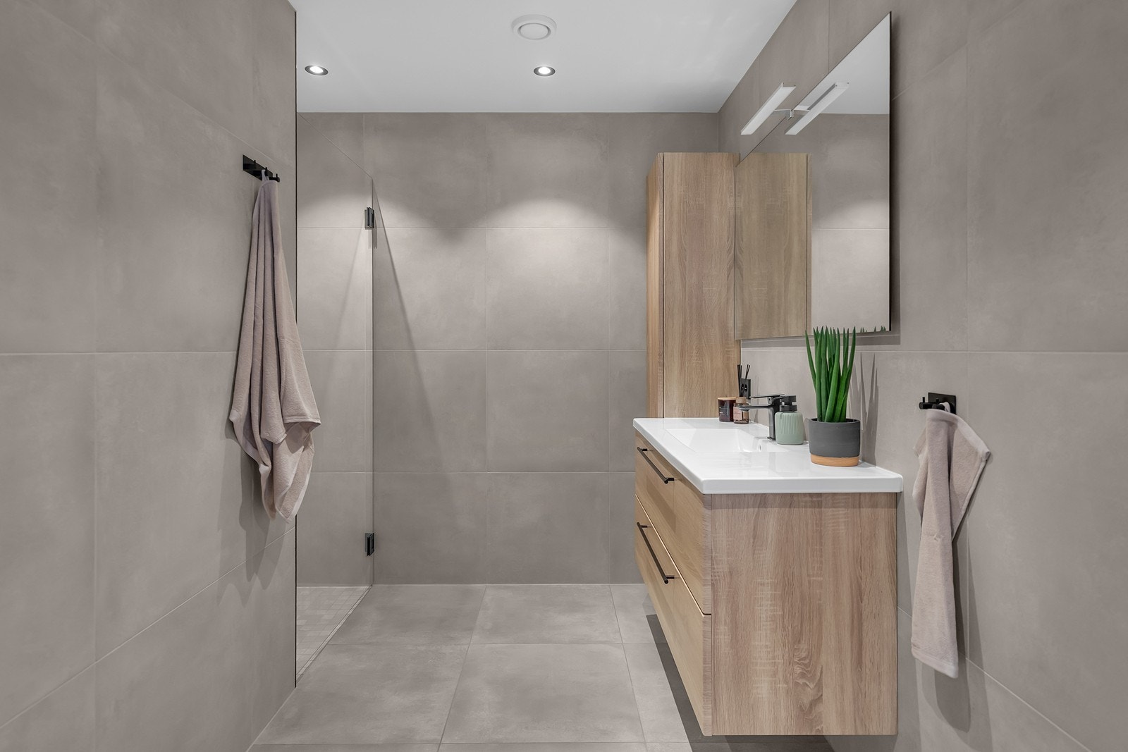 Bad med toalett, dusjhjørne, servant med skuffeløsning og høyskap på vegg for oppbevaring. Galleribilde