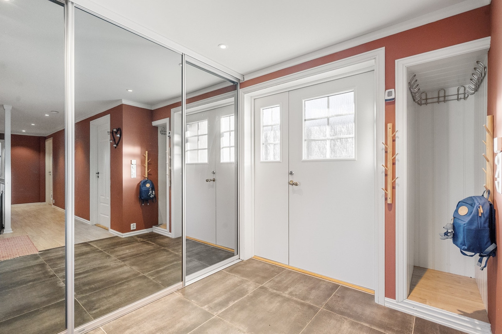 Romslig entré med flott skyvedørsgarderobe med speilfronter, noe som gir dybde til rommet. Galleribilde