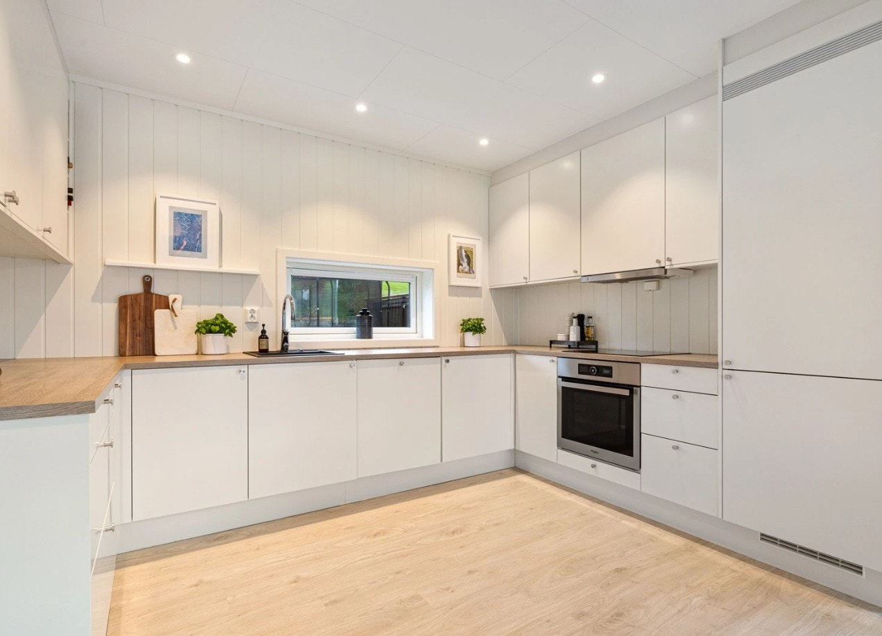 Pent kjøkken som har godt med skap- og benkeplass og integrerte hvitevarer Galleribilde