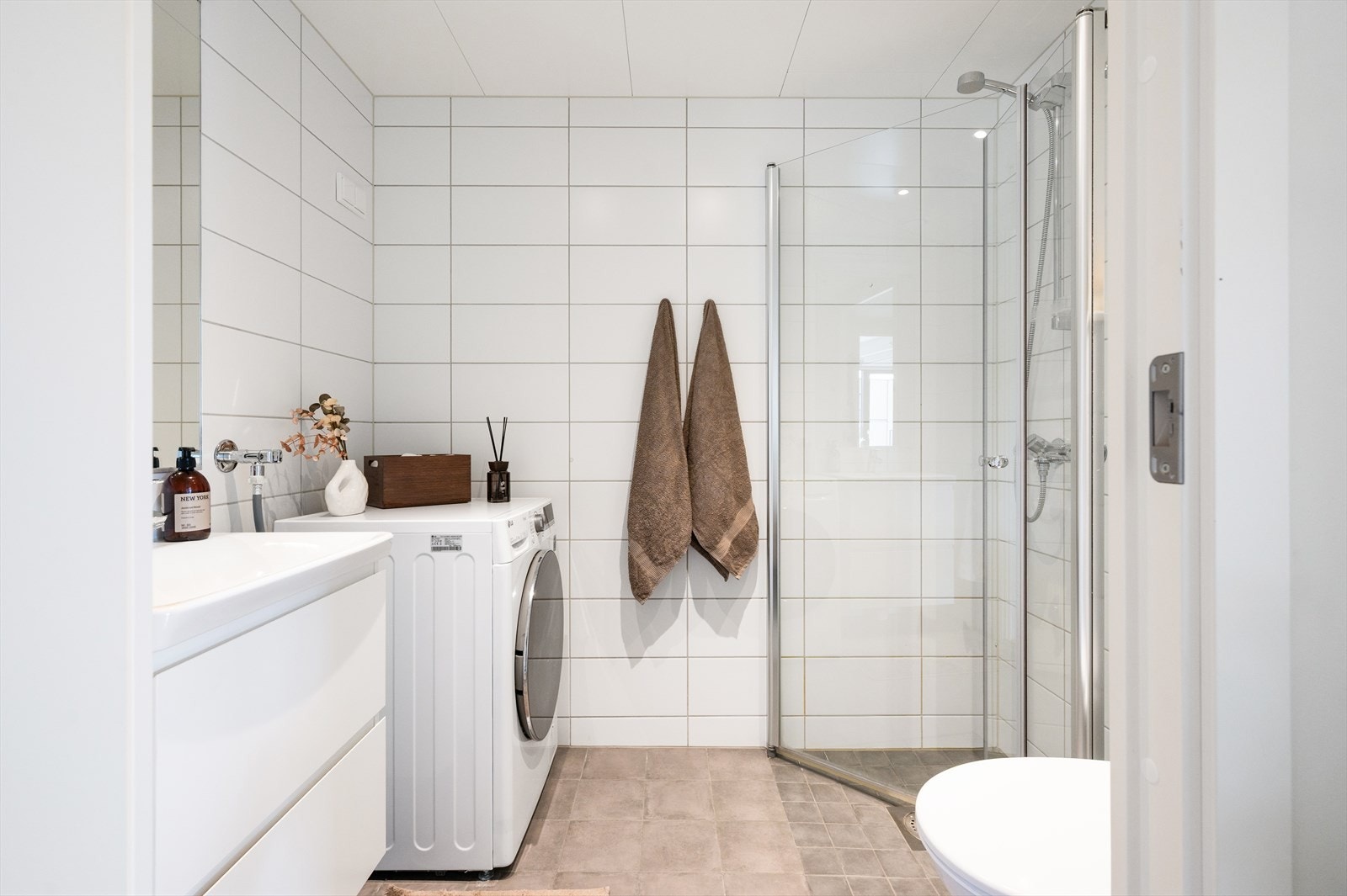 Pent og moderne baderom med dusjnisje med innfellbare glassdører, servant med ettgreps blandebatteri og vegghengt toalett. Galleribilde