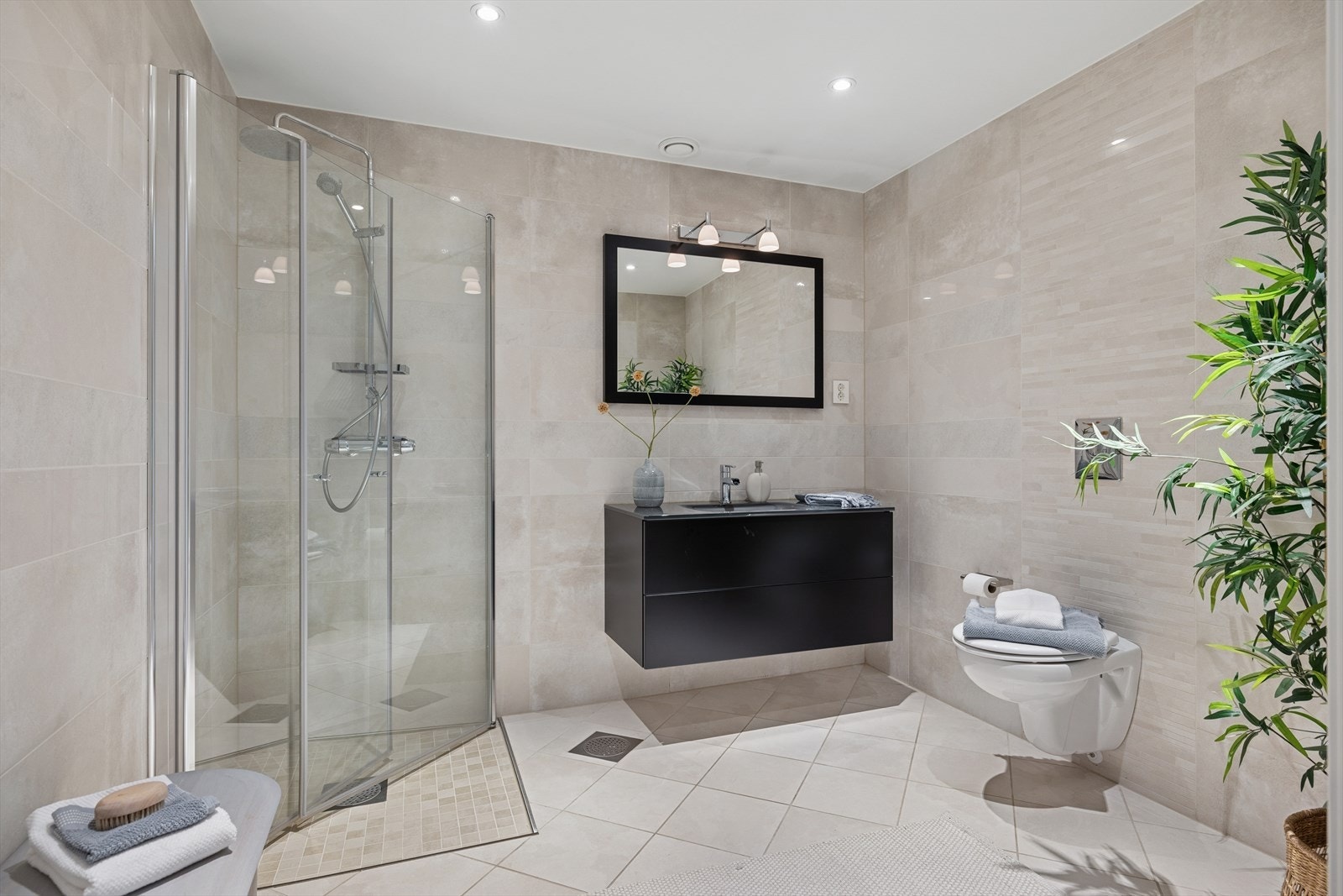 Baderom II har fislagte vegger og gulv. Servant i innredning, vegghengt wc og dusjhjørne med glassvegger Galleribilde