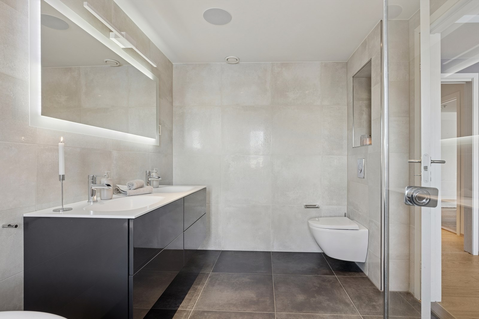 Hovedbaderom med delikate fliser på vegger og gulv. Vegghengt wc og skuffer i innredning Galleribilde