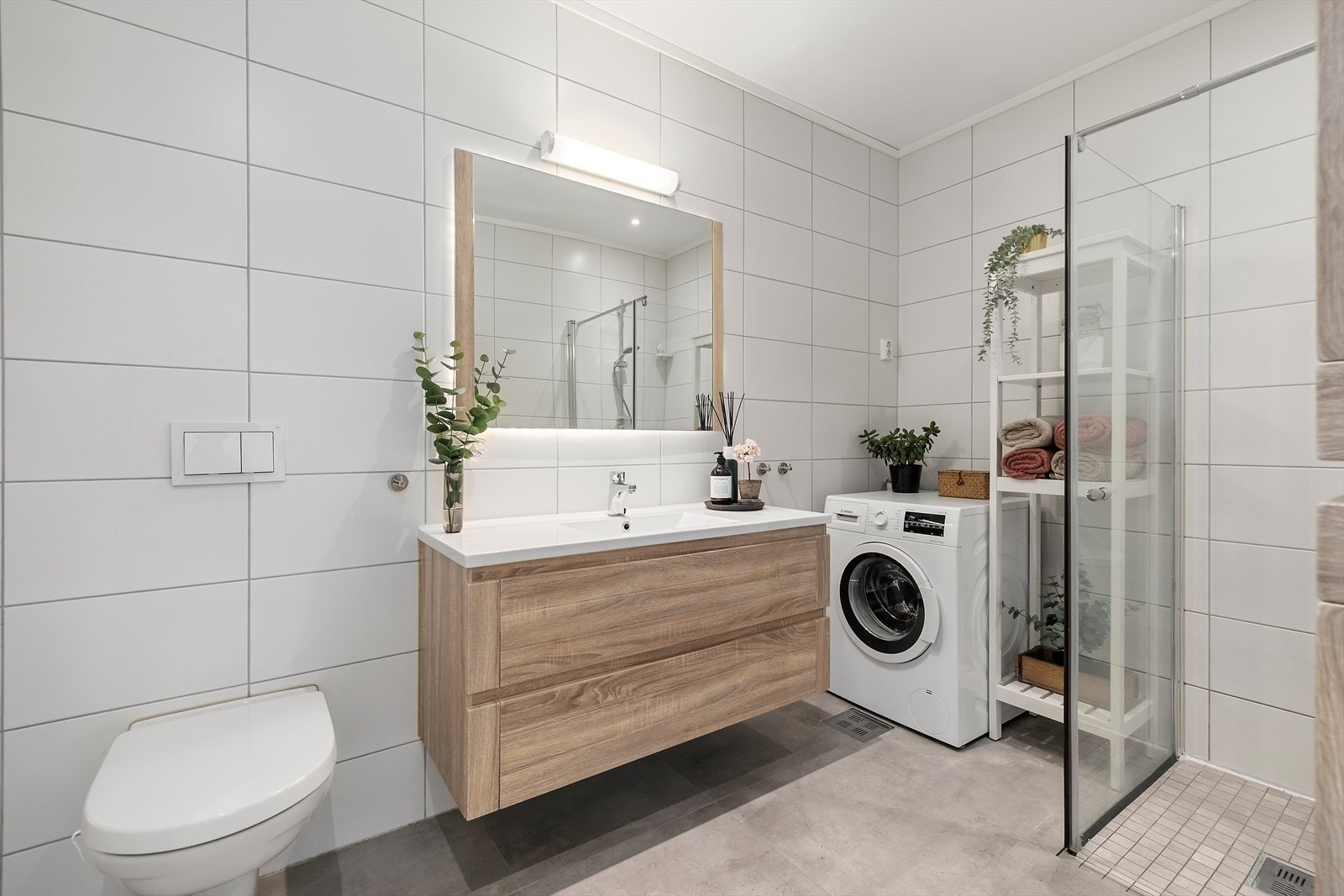 Flott bad med innredning med nedfelt servant, vegghengt speil, veggmontert toalett, dusjvegger/hjørne. Galleribilde