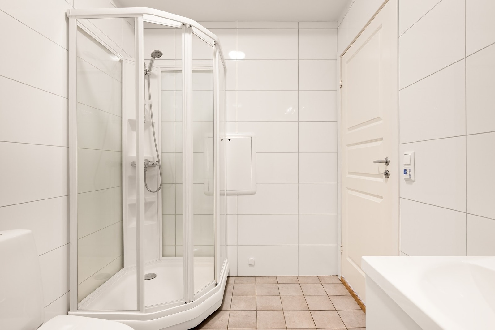 Badet er utstyrt med gulvstående wc, dusjkabinett, baderomsinnredning og opplegg for vaskemaskin Galleribilde