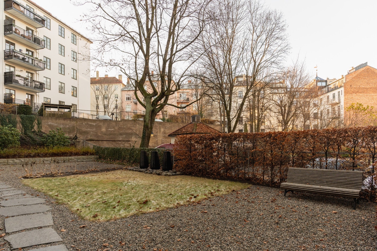 Bakgården byr på et skjermet uteområde med beplantning og benk. Galleribilde