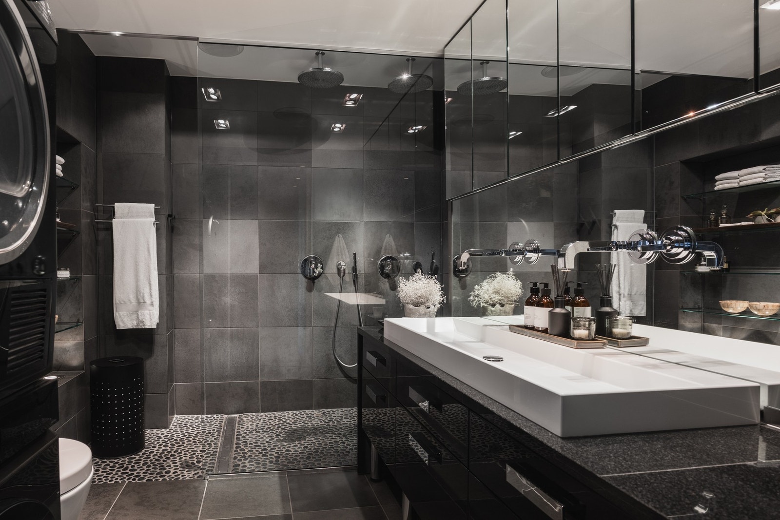 Smakfullt bad, der mørke fliser, rene linjer og gjennomførte materialvalg skaper en dempet atmosfære. Galleribilde