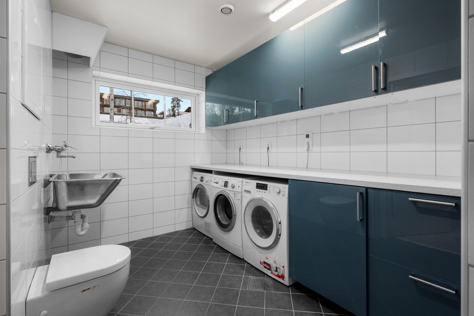 Det flislagte vaskerommet er både praktisk og velutstyrt, med vannbåren gulvvarme og opplegg for dusj