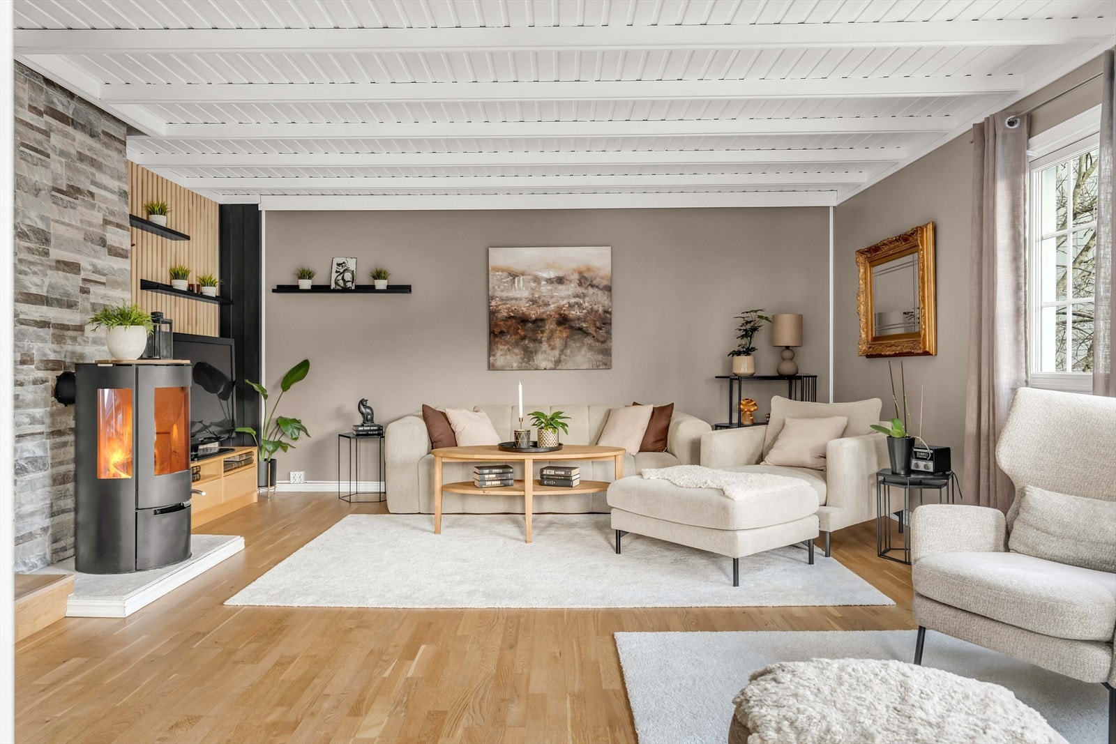 Stuen er pen og romslig, med en stor vindusflate som slipper inn rikelig med dagslys, samtidig som den bringer noe av det grønne inn i rommet. Galleribilde