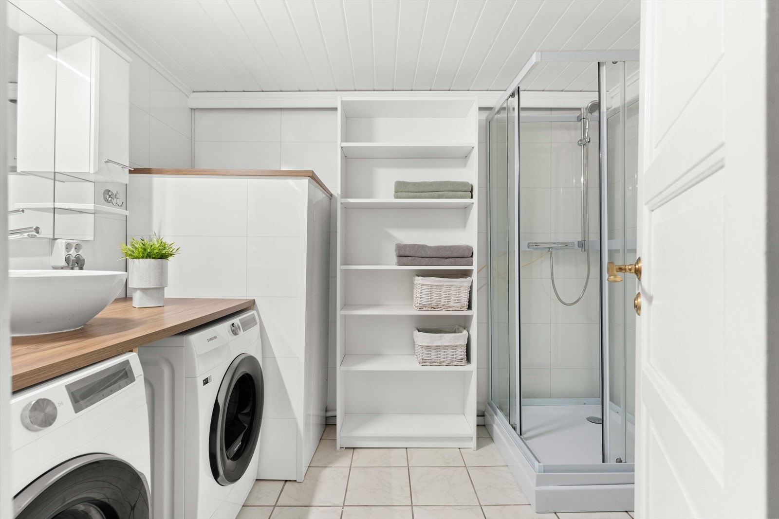 Boligens vaskerom er innredet med dusjkabinett, opplegg for vaskemaskin, tørketrommel, overskap med speil og gode oppbevaringsmuligheter. Galleribilde