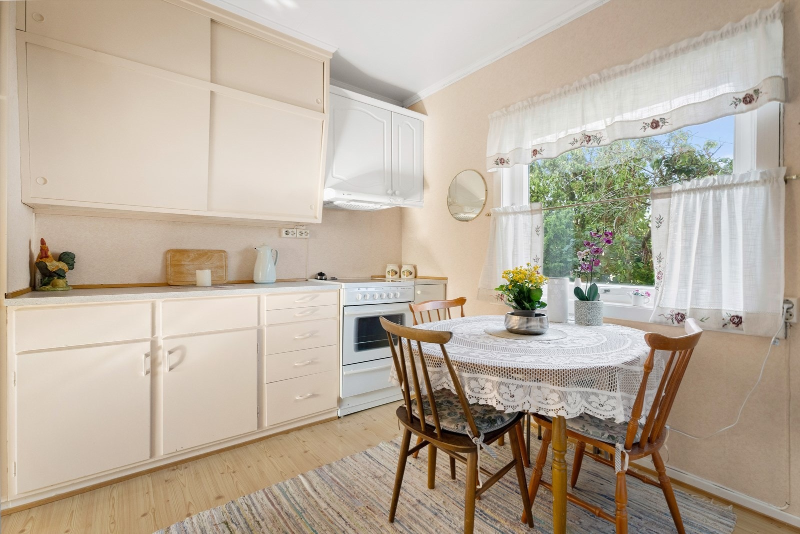 Kjøkkenet i 1. etasje har en eldre innredning med lyse, slette fronter og laminert benkeplate med nedfelt oppvaskkum Galleribilde