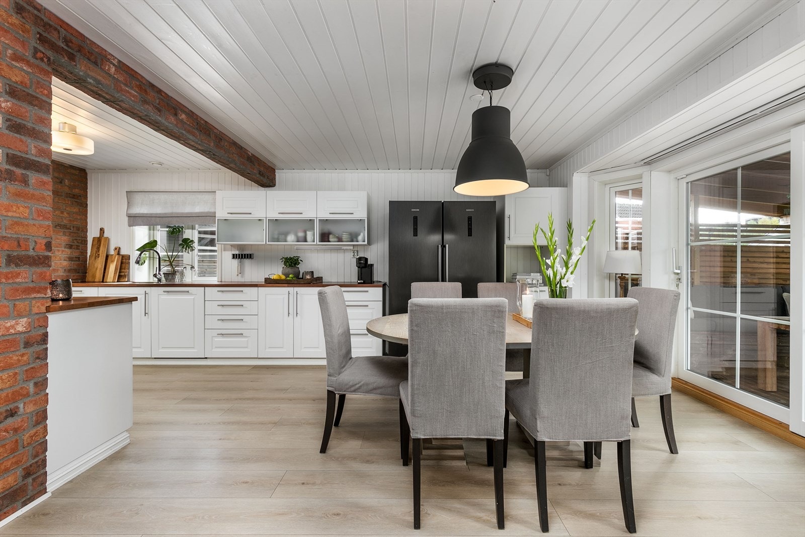 Samme type laminatgulv med varme bidrar til en flytende overgang mellom rommene. To teglsteinsvegger gir ekstra liv til kjøkkenet. Galleribilde