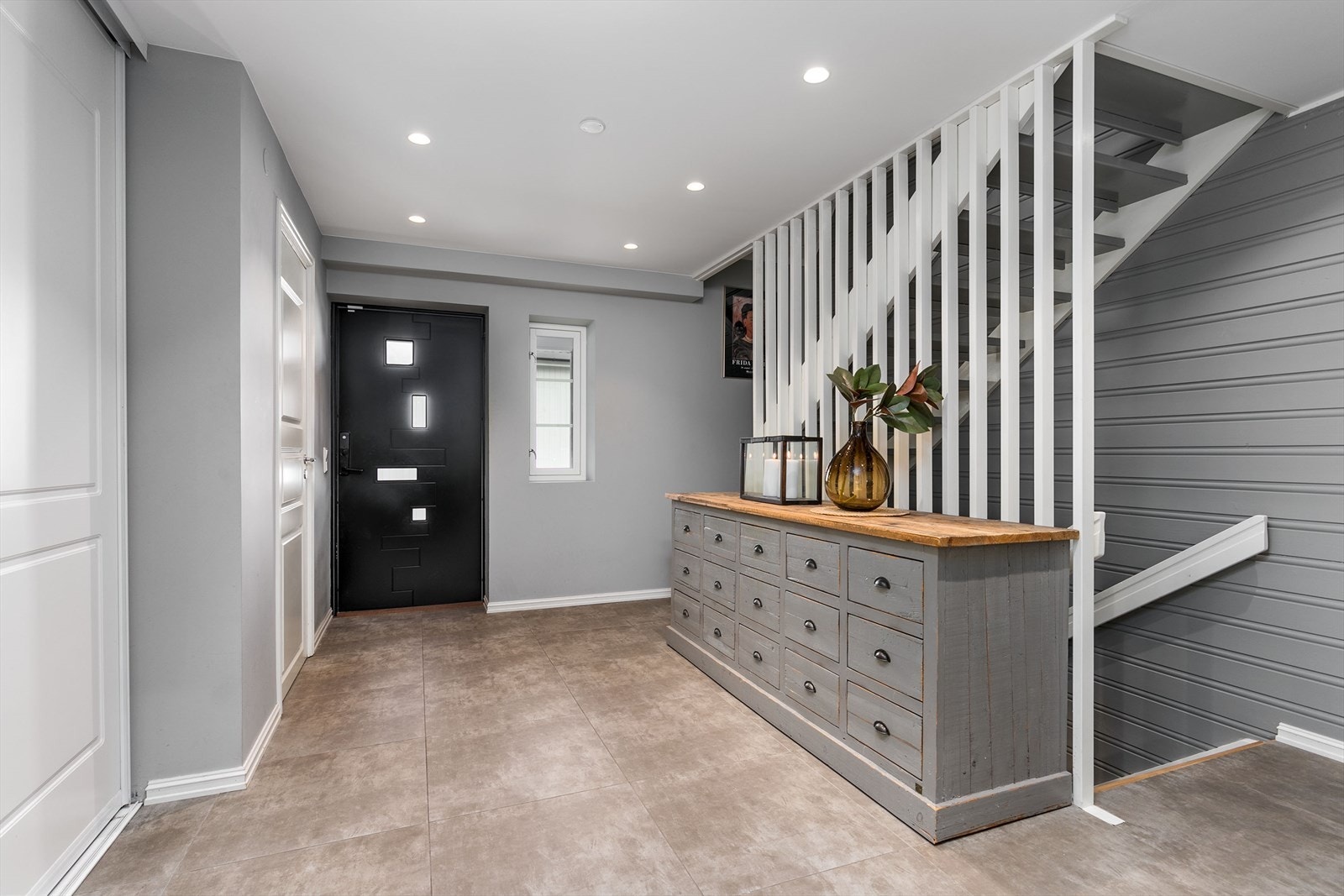 Flisene fortsetter inn på et praktisk gjestetoalett, og hallen har mye oppbevaring i en stor, plassbygd skyvedørsgarderobe. Galleribilde