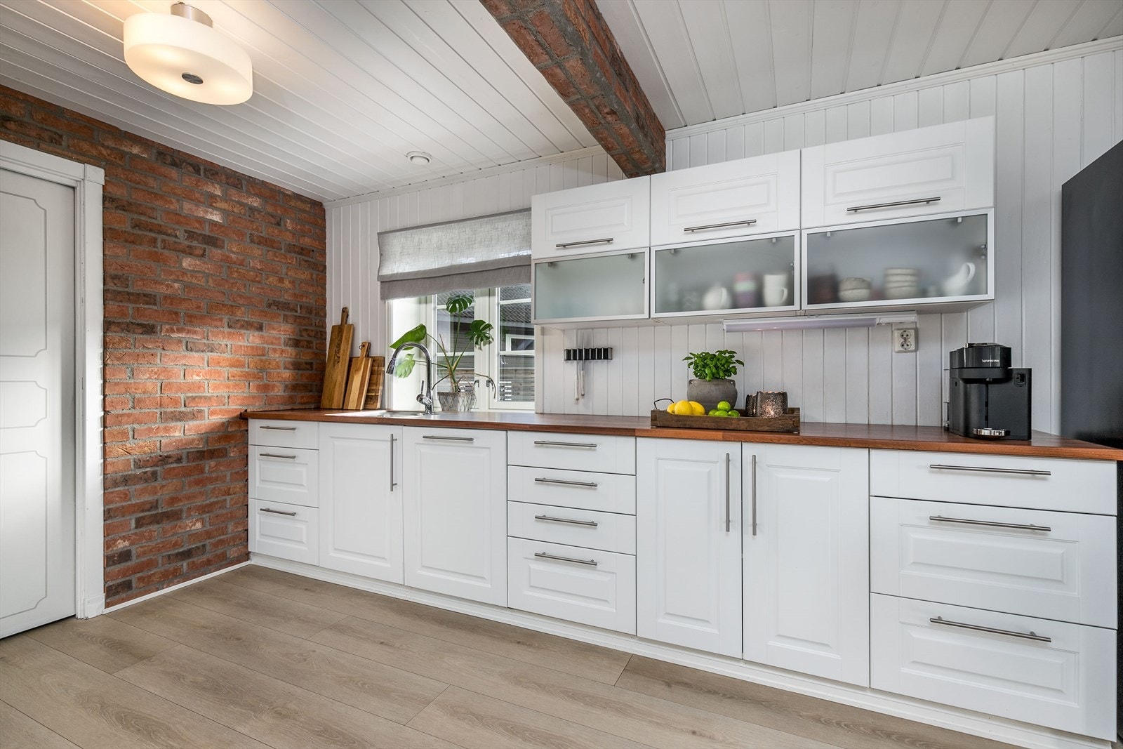 Selve kjøkkenet har en luftig utforming med god skap- og benkeplass - her kan hele familien bli med på matlagingen. Innredningen er fra 2008, med hvite, profilerte fronter, frostede overskap, heltre benkeplater og nedfelt oppvaskkum. Galleribilde