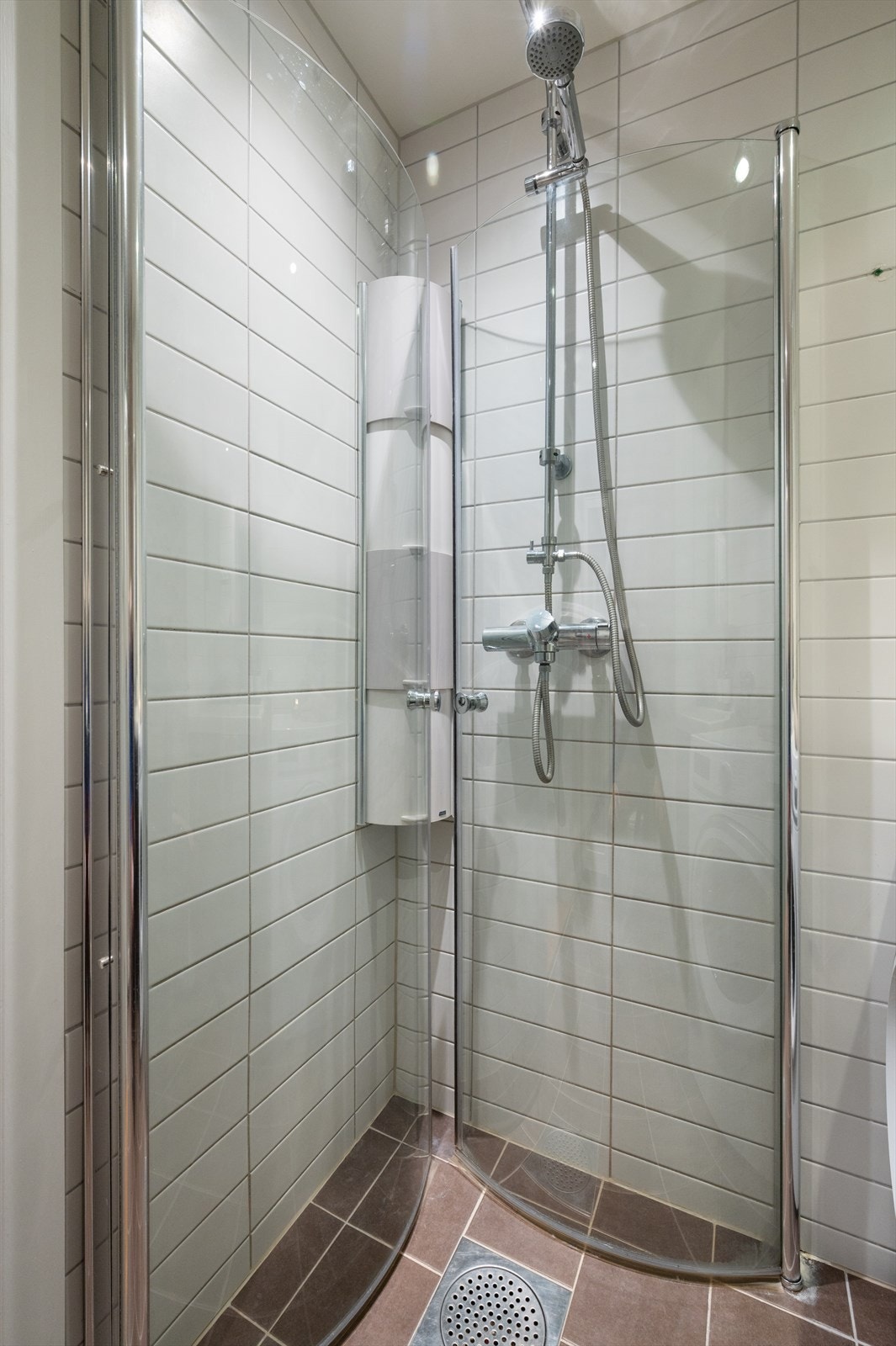 Videre har badet dusjhjørne med innfellbare dører i glass og vegghengt klosett. Galleribilde
