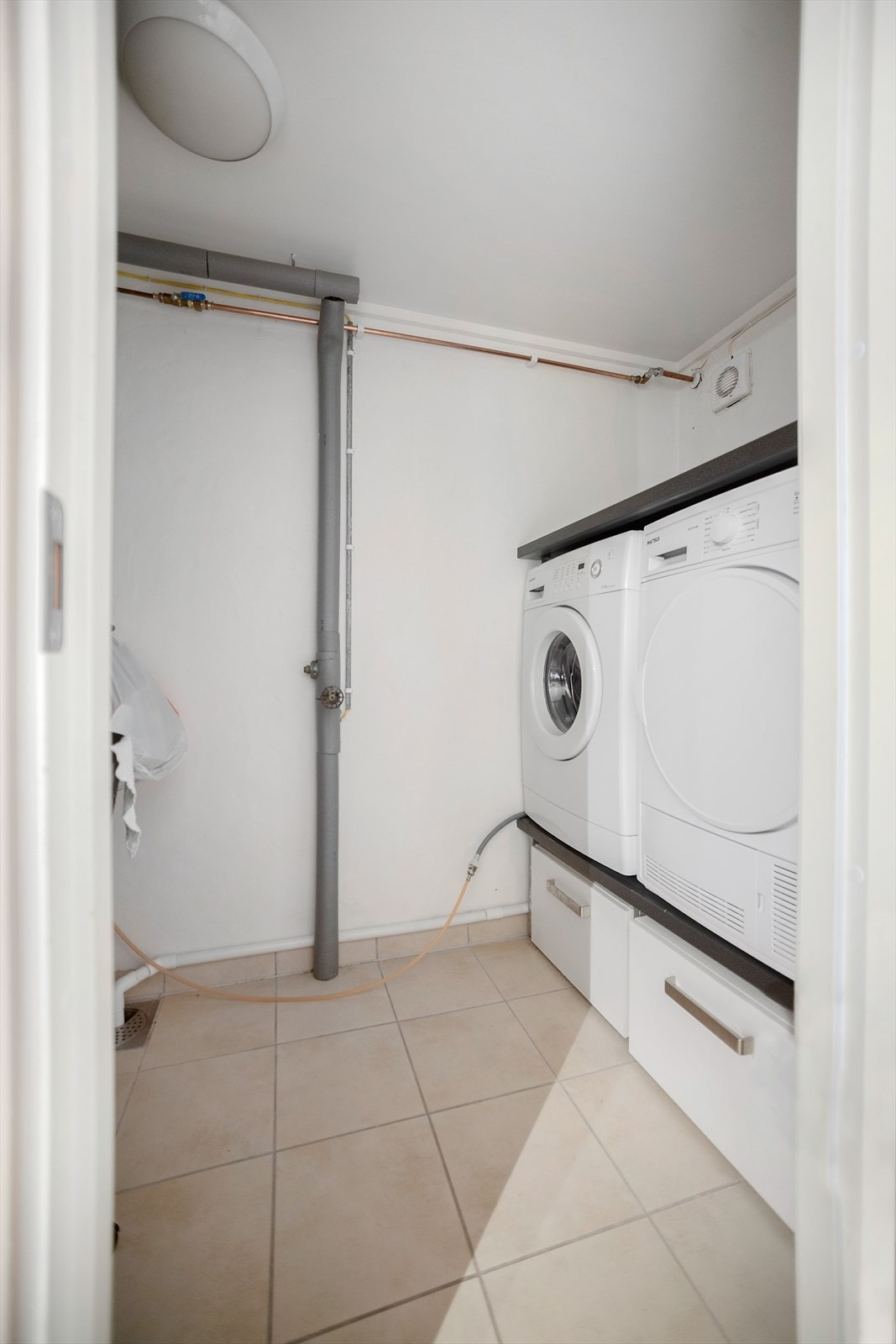 Praktisk vaskerom med flislagt gulv med varmekabler Galleribilde