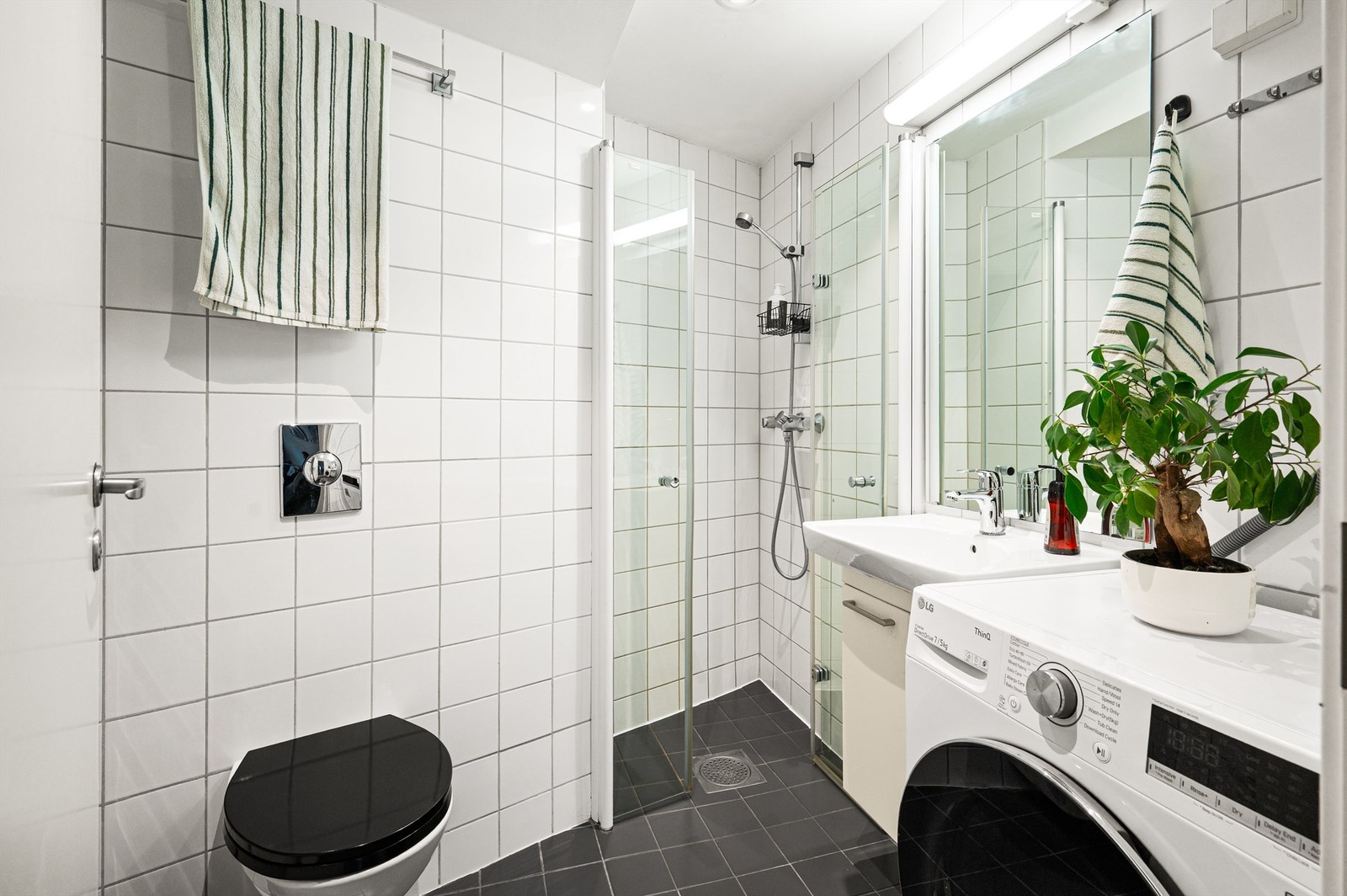 Pent, flislagt bad med vegghengt klosett og innfellbare dusjvegger. Galleribilde