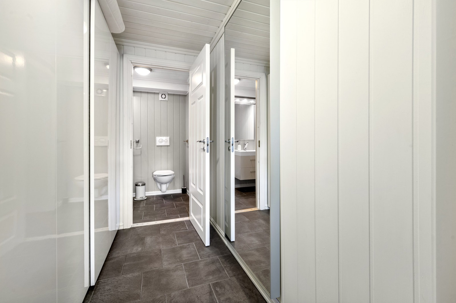 Romslig gang med adkomst til alle rom i underetasjen. Her har du plass til garderobeskap og diverse mindre møblement. Galleribilde