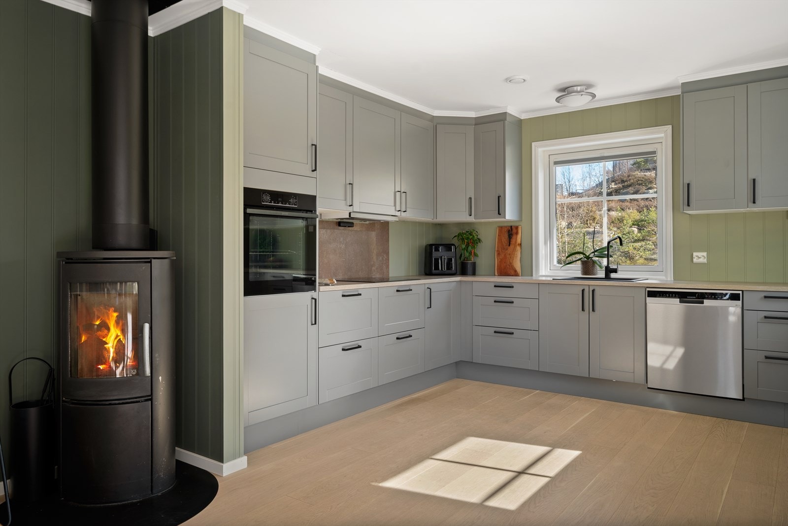 Stuen/kjøkken har stemningsfull vedovn med glassfelt, stålpipe og praktisk plate på gulvet. Galleribilde