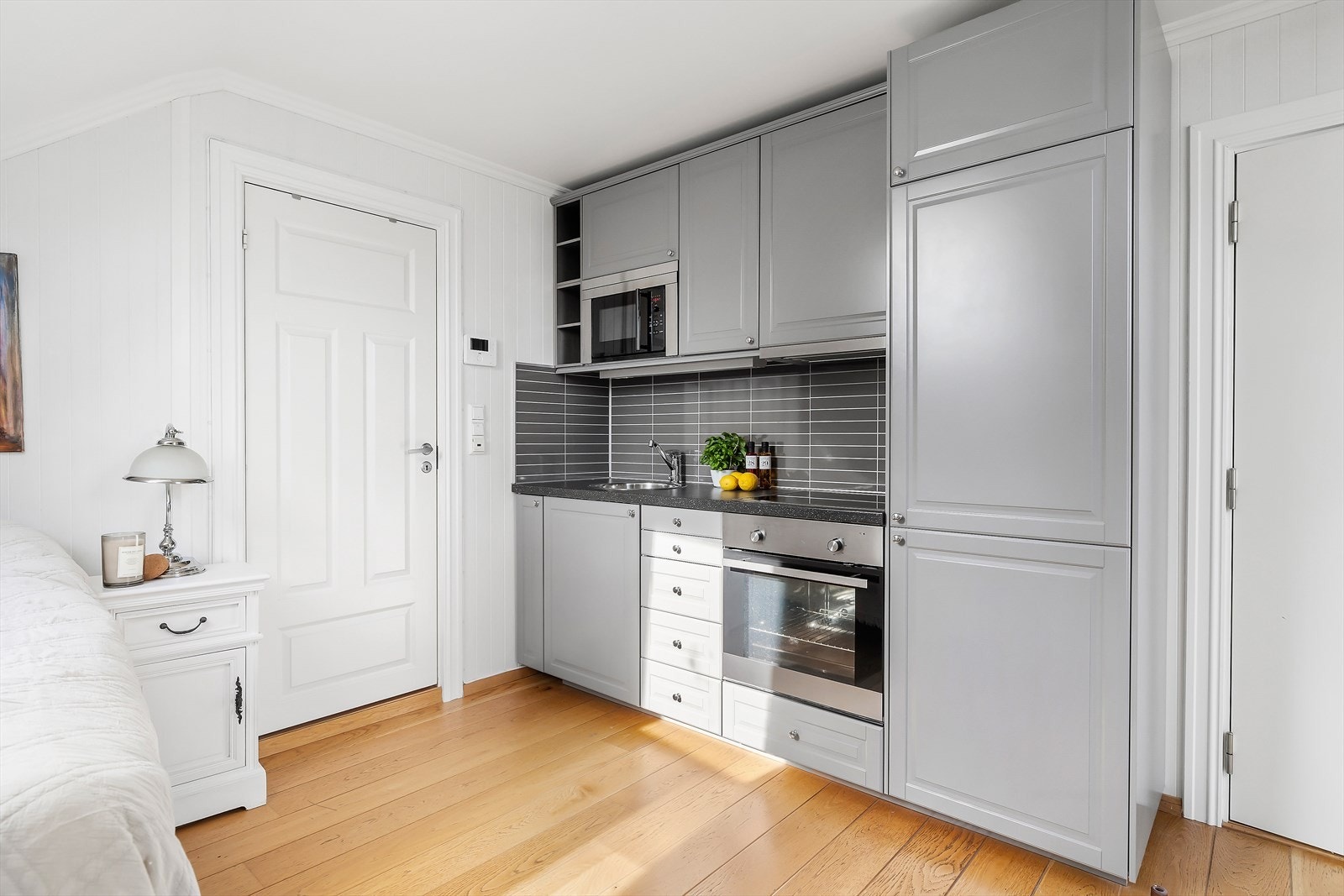 Kjøkken i hybel/soverommet med profilerte fronter og benkeplate i høytrykkslaminat. Integrert kjøl/fryseskap, komfyr, micro og platetopp. Galleribilde