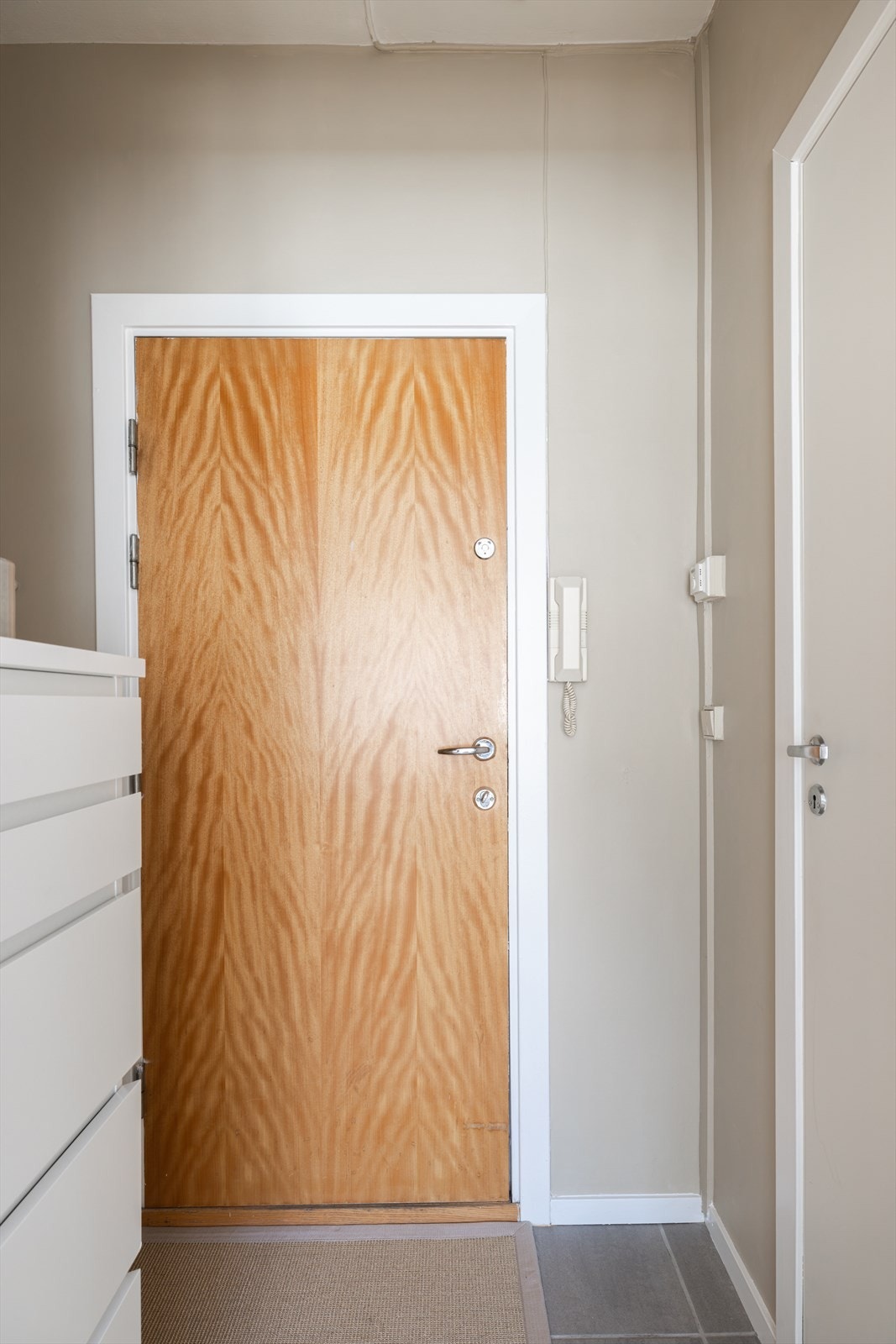 Du blir møtt av innbydende entré med flislagt gulv, som gir et godt førsteinntrykk av leiligheten. Galleribilde